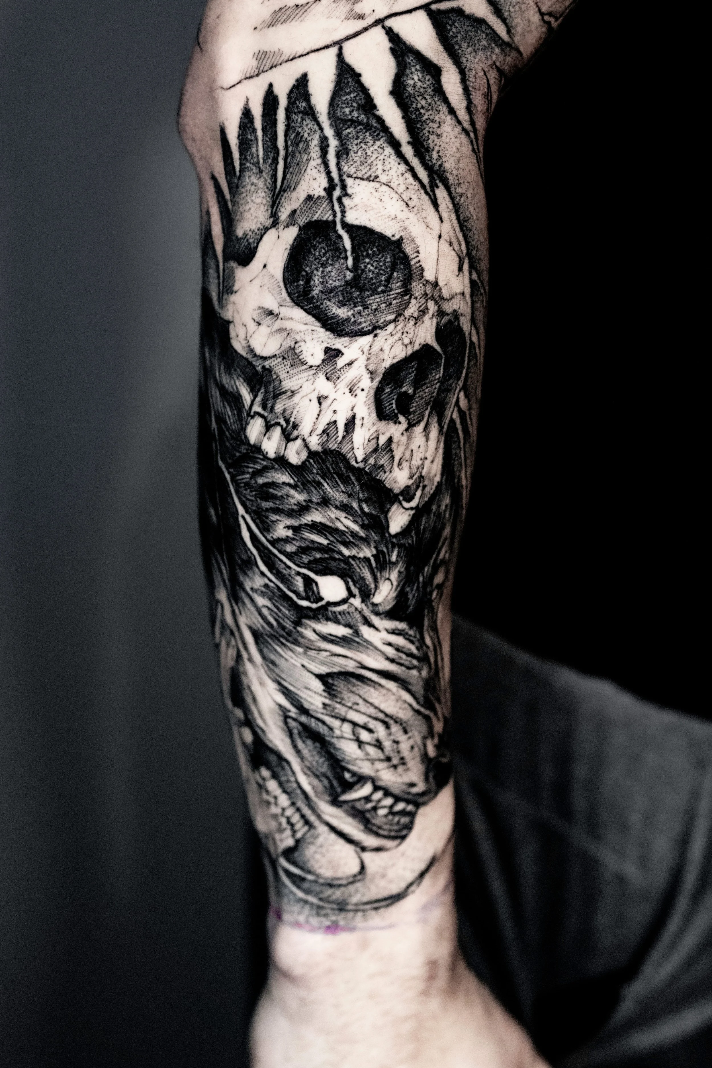 Black-and-gray skull and animal forearm tattoo.