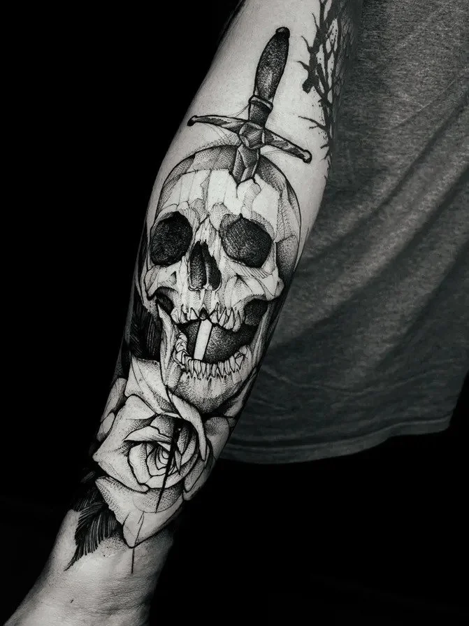 Black-and-gray skull pierced by sword forearm tattoo.