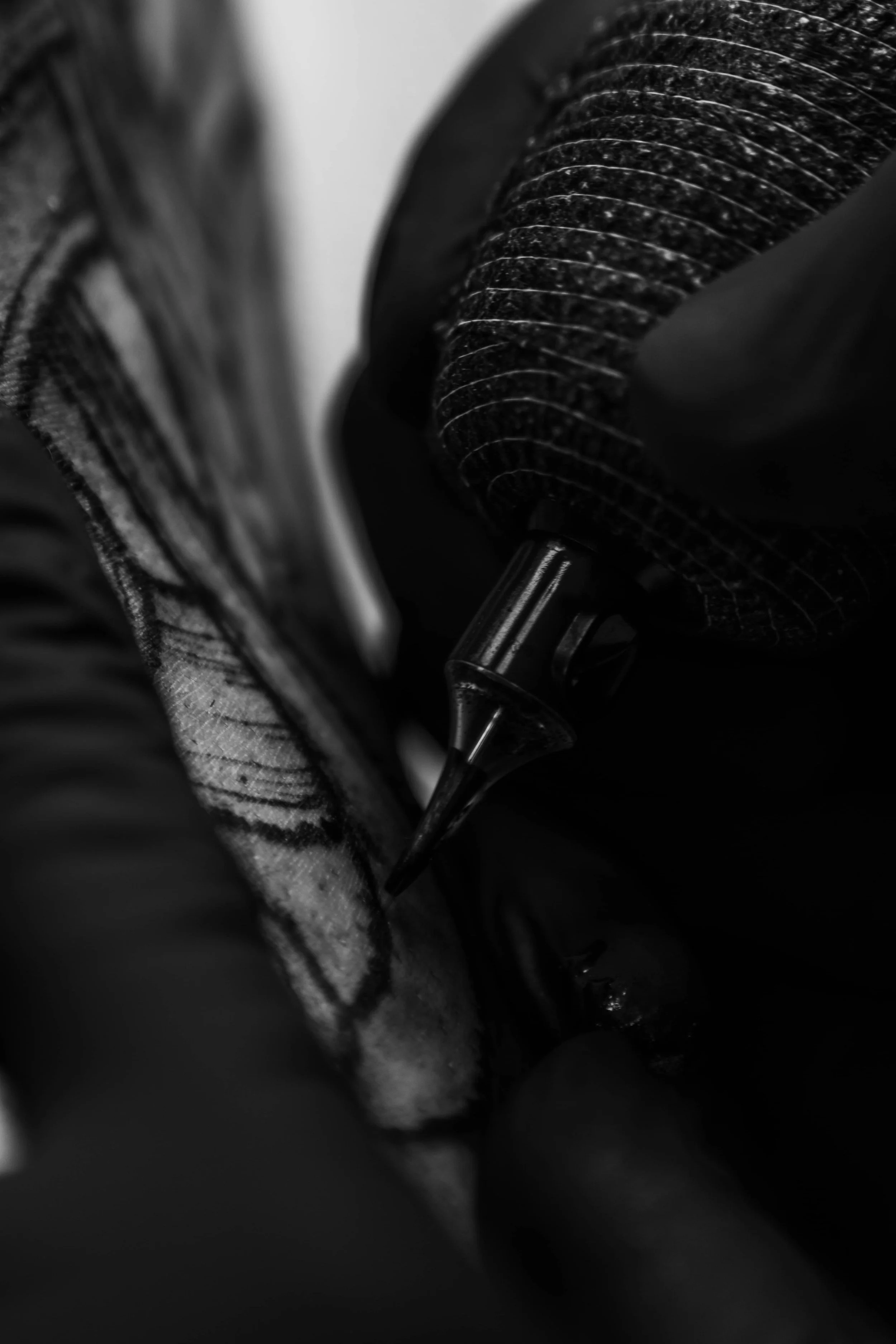 A close-up of a tattoo needle cartooning ink into skin, with a gloved hand holding the needle.