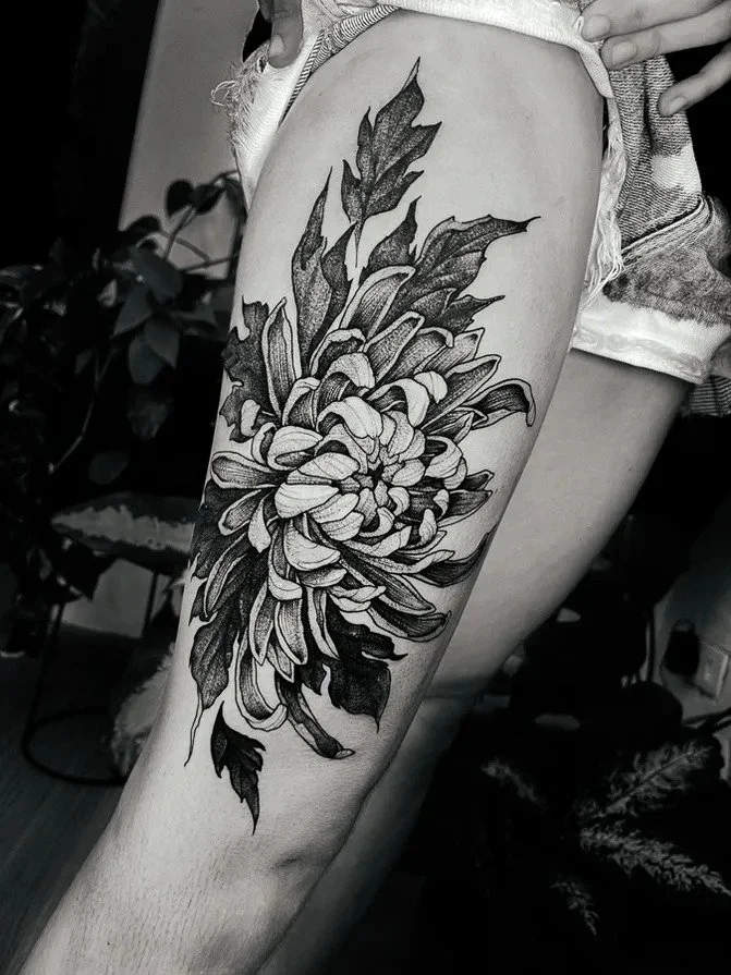 Black-and-gray floral thigh tattoo with detailed petals.