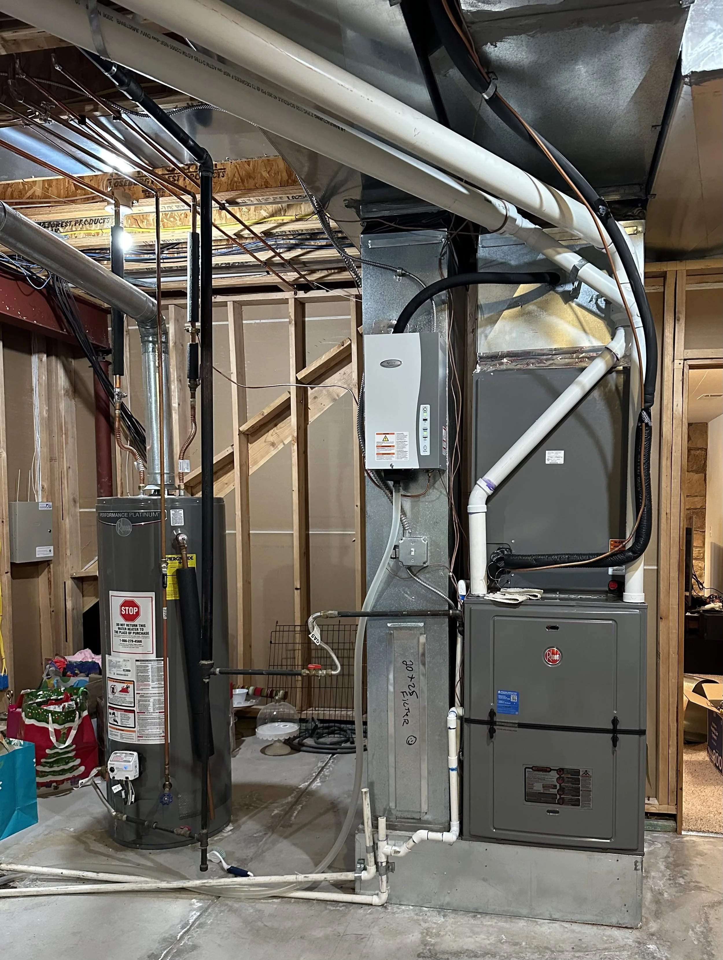 Indoor view of HVAC system and water heater installed in a basement with exposed wooden framing.