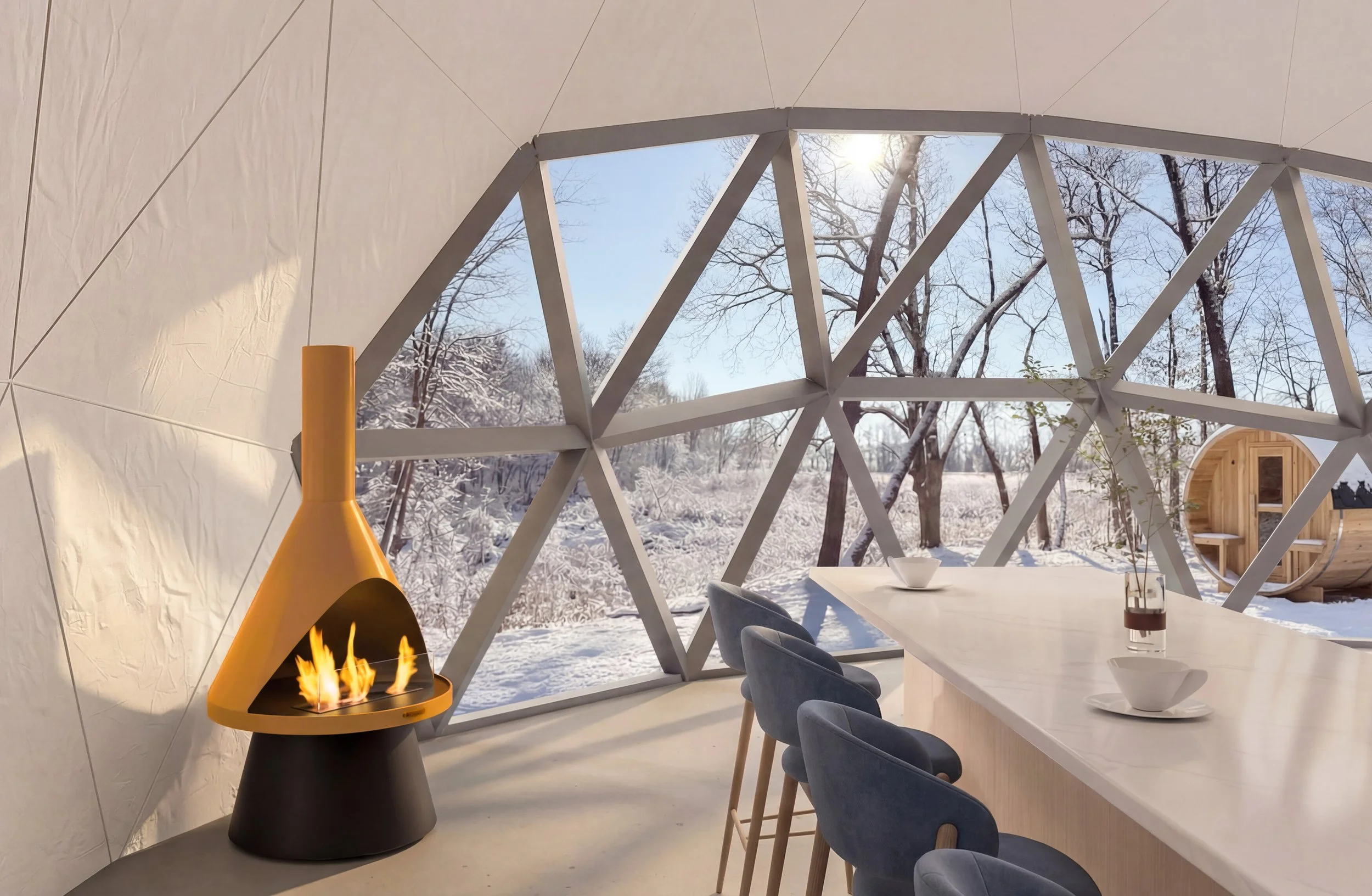 Interior view of a modern yurt with a fire burning in a yellow and black fireplace, a long white table with white bowls and a glass of a dark beverage, and blue chairs, with large geometric windows showing a snowy winter landscape outside under a bright sun.