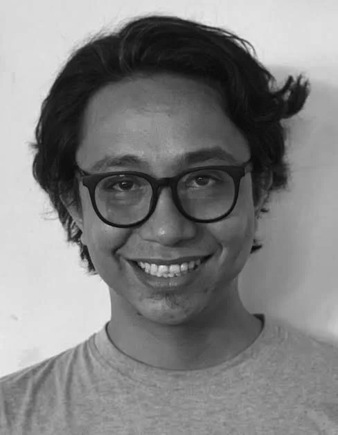 A Black and white photo of Nono Sumampouw with glasses and wavy hair.