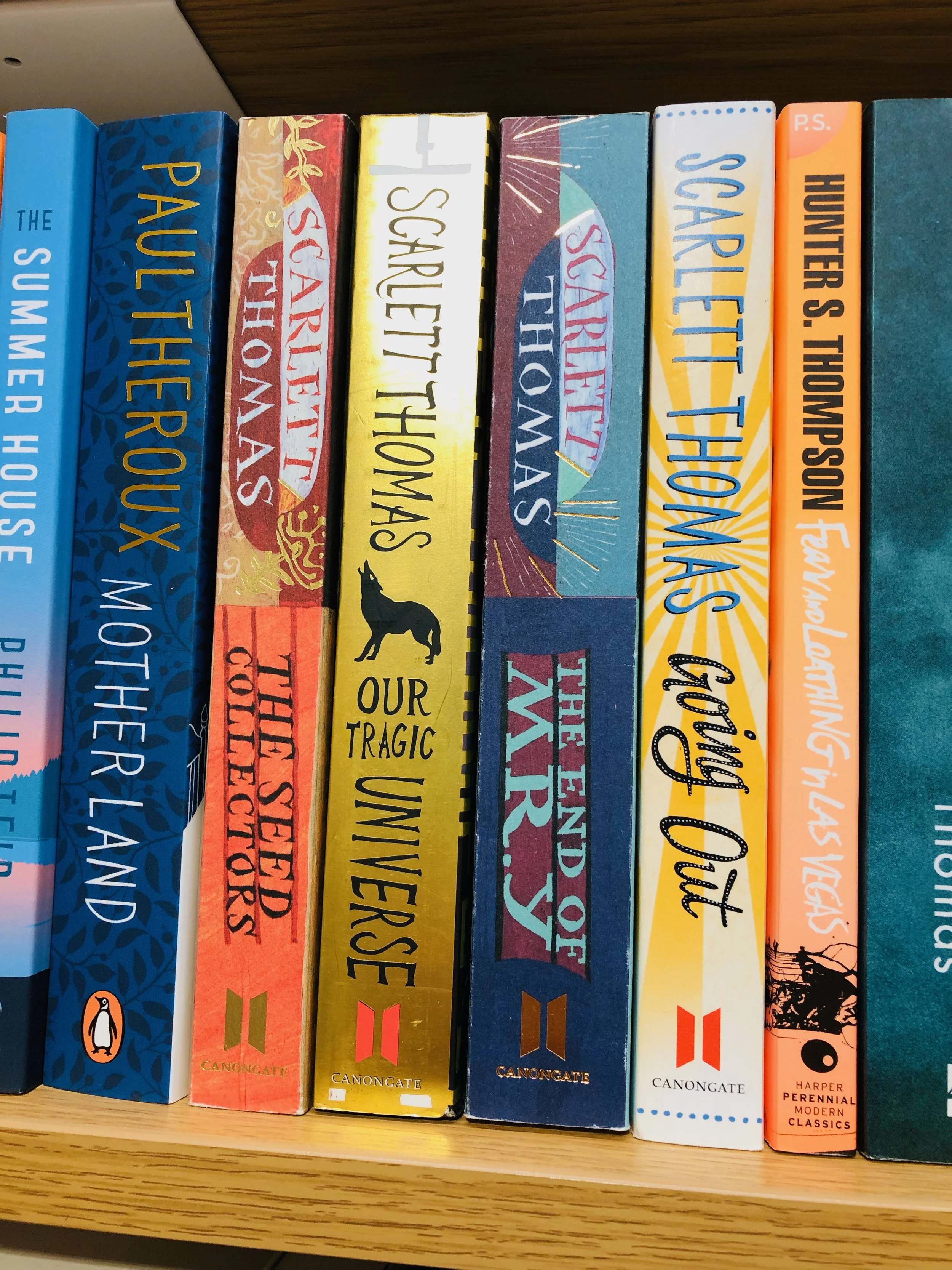 A row of books on a bookshelf, with titles including 'The Summer House,' 'Pault thex,' 'Scarlet Thorns,' 'Sparlet Thorns,' 'Our Tragic Unvers,' 'The Marias,' 'Sparlet Thorns,' 'Huntor S. Thempson,' and others.