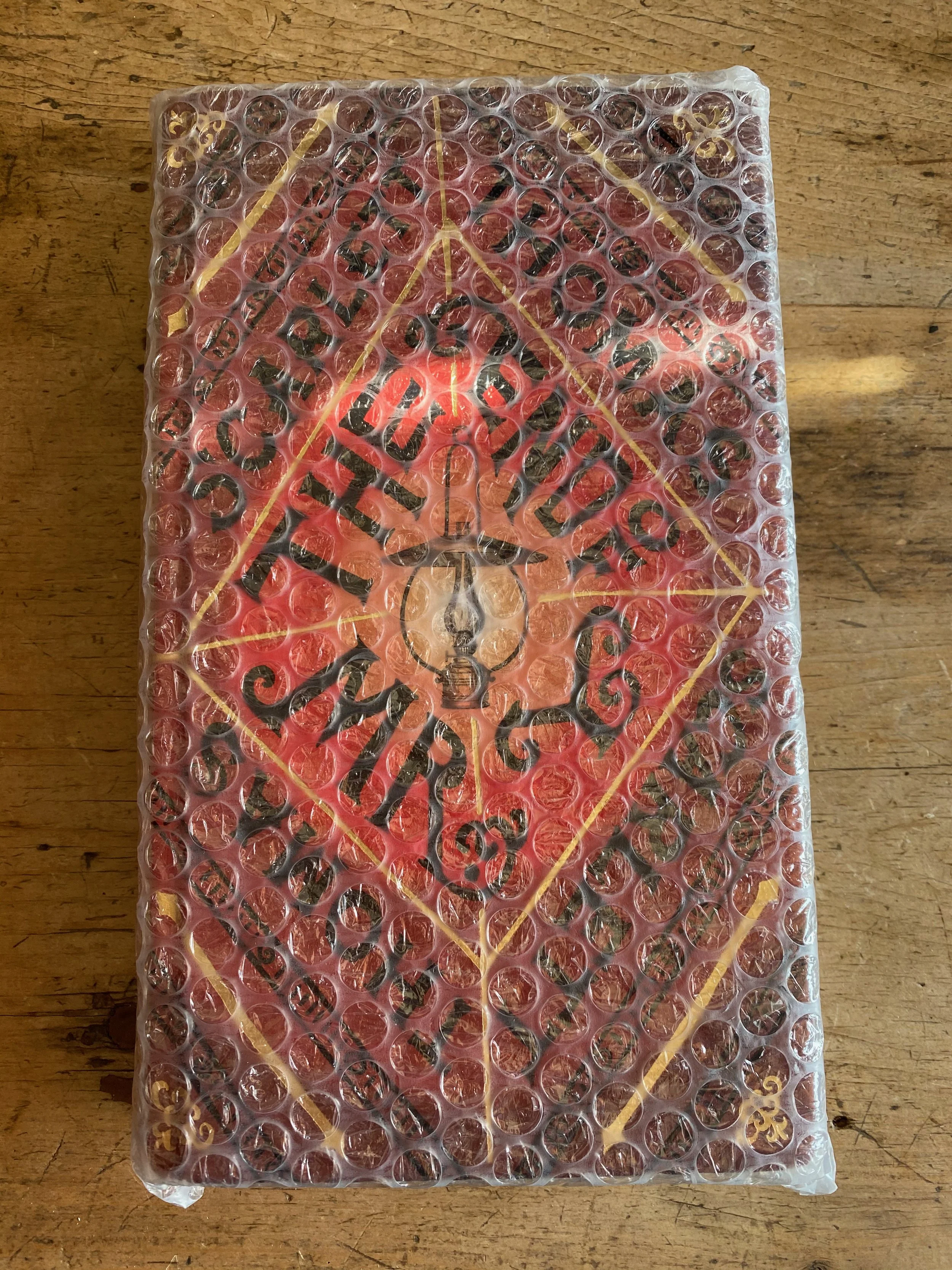 A book wrapped in bubble wrap placed on a wooden surface.