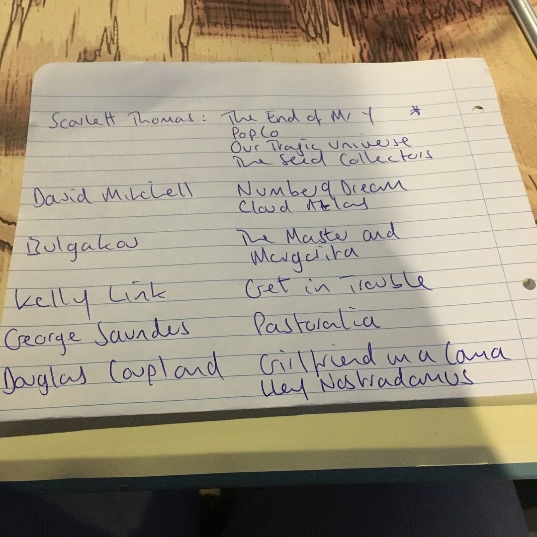 Lined notepad with handwritten names and notes; appears to be a list of book titles and authors.