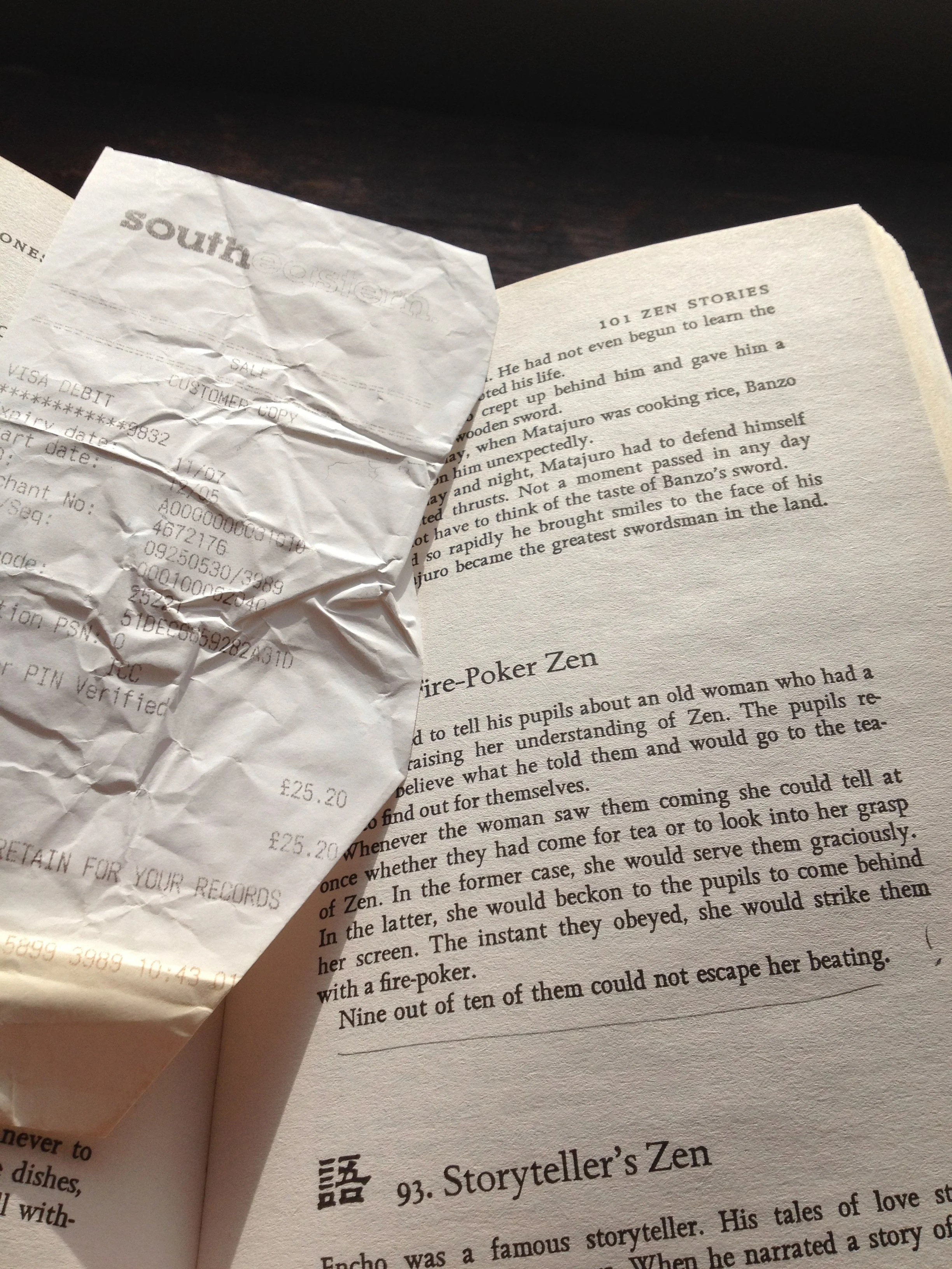 Open book and crumpled receipt on a dark wooden surface.