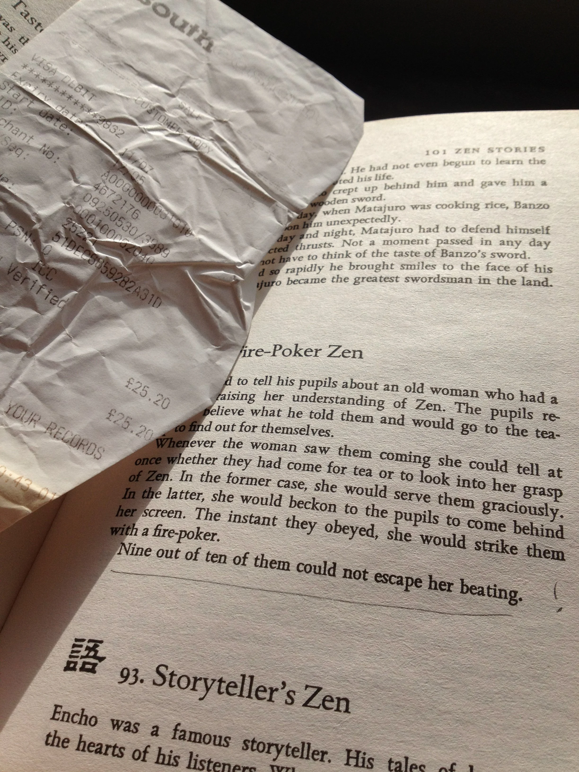 Crumpled receipt placed on open book page with text from a story about Zen and a storyteller.
