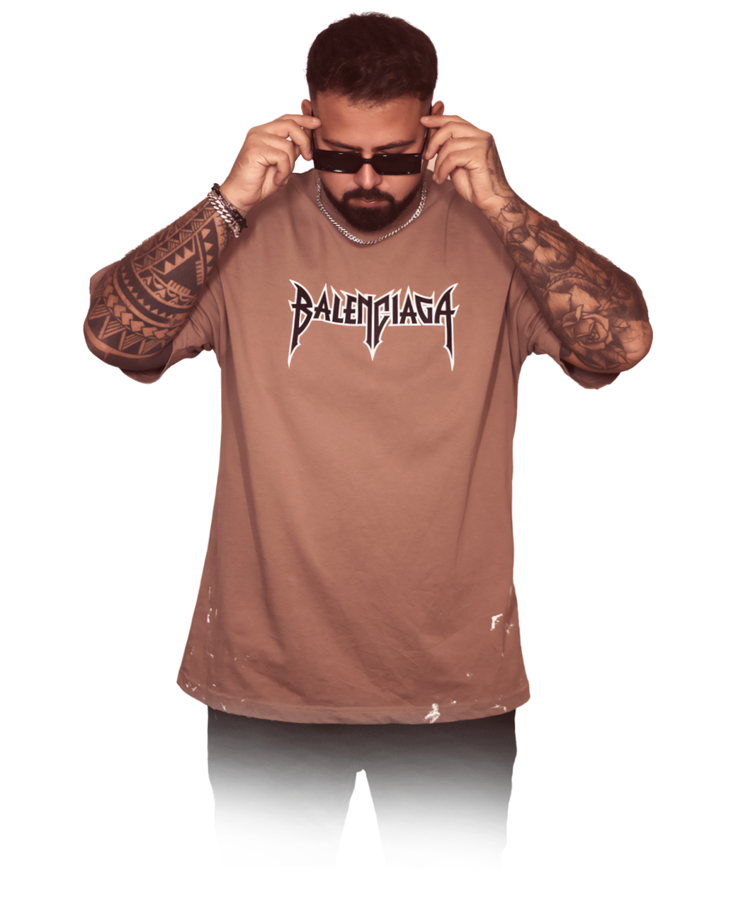 Junger Mann mit Tattoos trägt ein bräunliches T-Shirt mit dem Logo 'Balenciaga' und zieht Sonnenbrille auf, während er nach unten schaut.