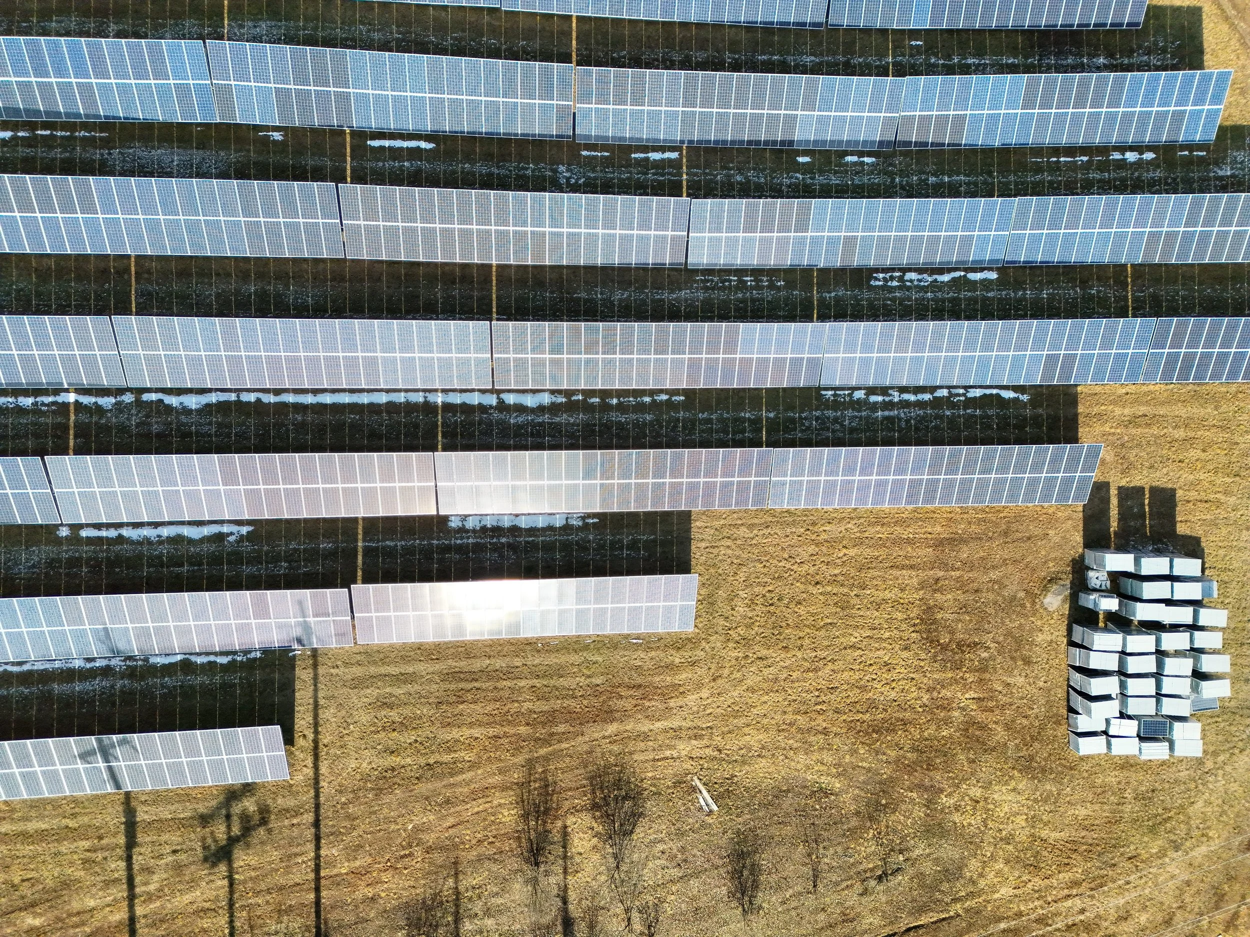 Aerial view of a solar farm with multiple rows of solar panels installed on a grassy field.
