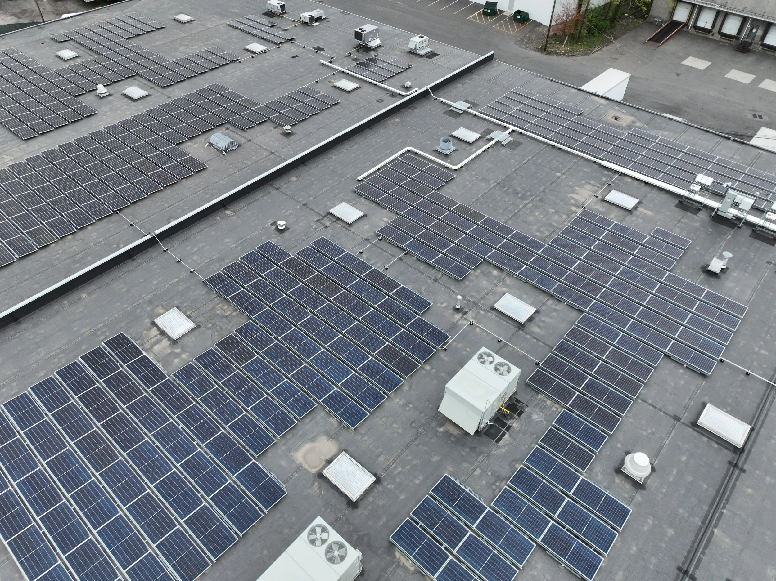 A rooftop with rows of solar panels and HVAC units.