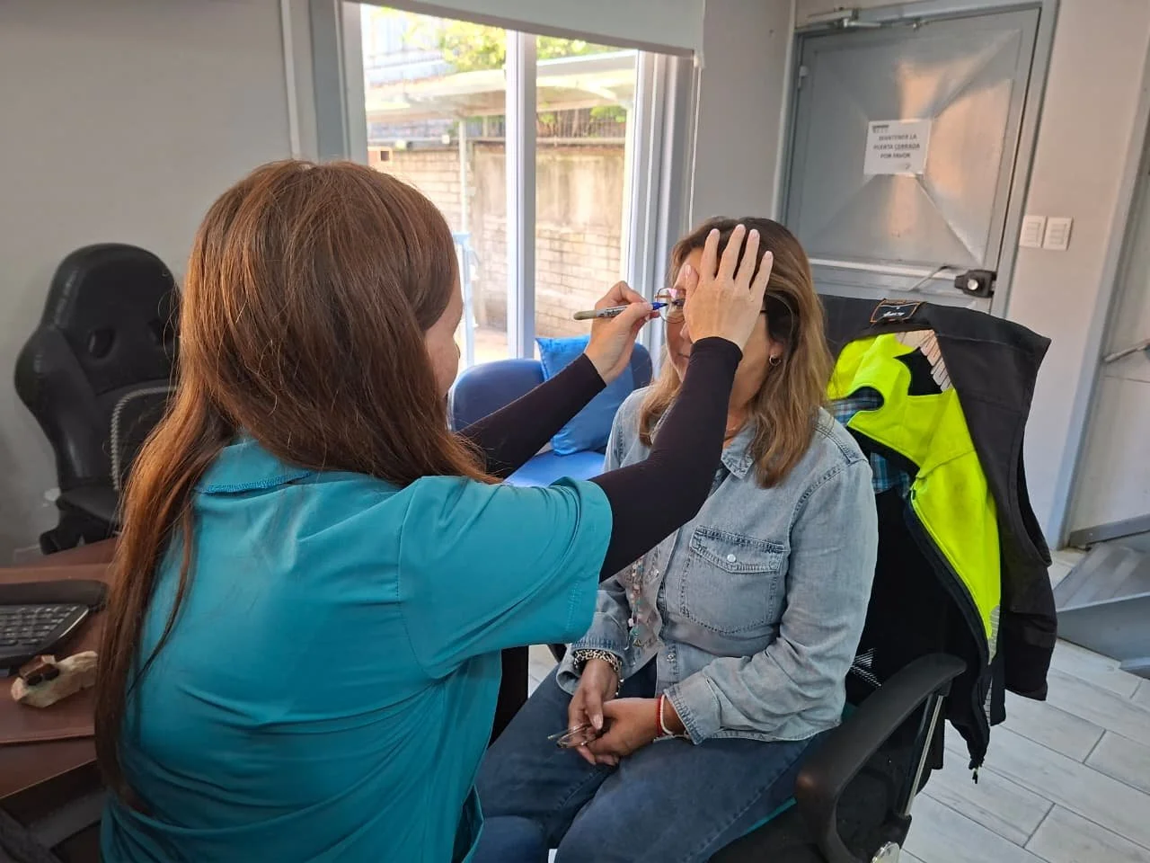 Una mujer recibe un maquillaje de una profesional en una oficina