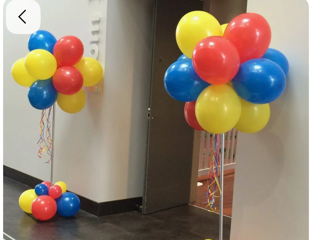 Colorful balloons in red, blue, and yellow arranged in clusters and attached to poles, likely for decoration at an event or celebration.