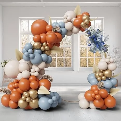 Colorful balloon arrangement with cream, blue, peach, gold, and white balloons, including floral accents, forming an arch in a bright room with large windows.