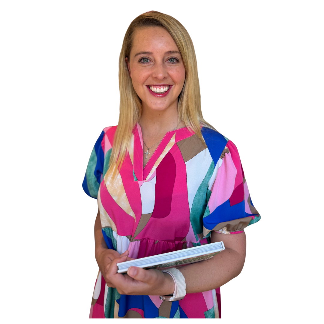 A smiling woman with blonde hair wearing a colorful, patterned dress holding a book.