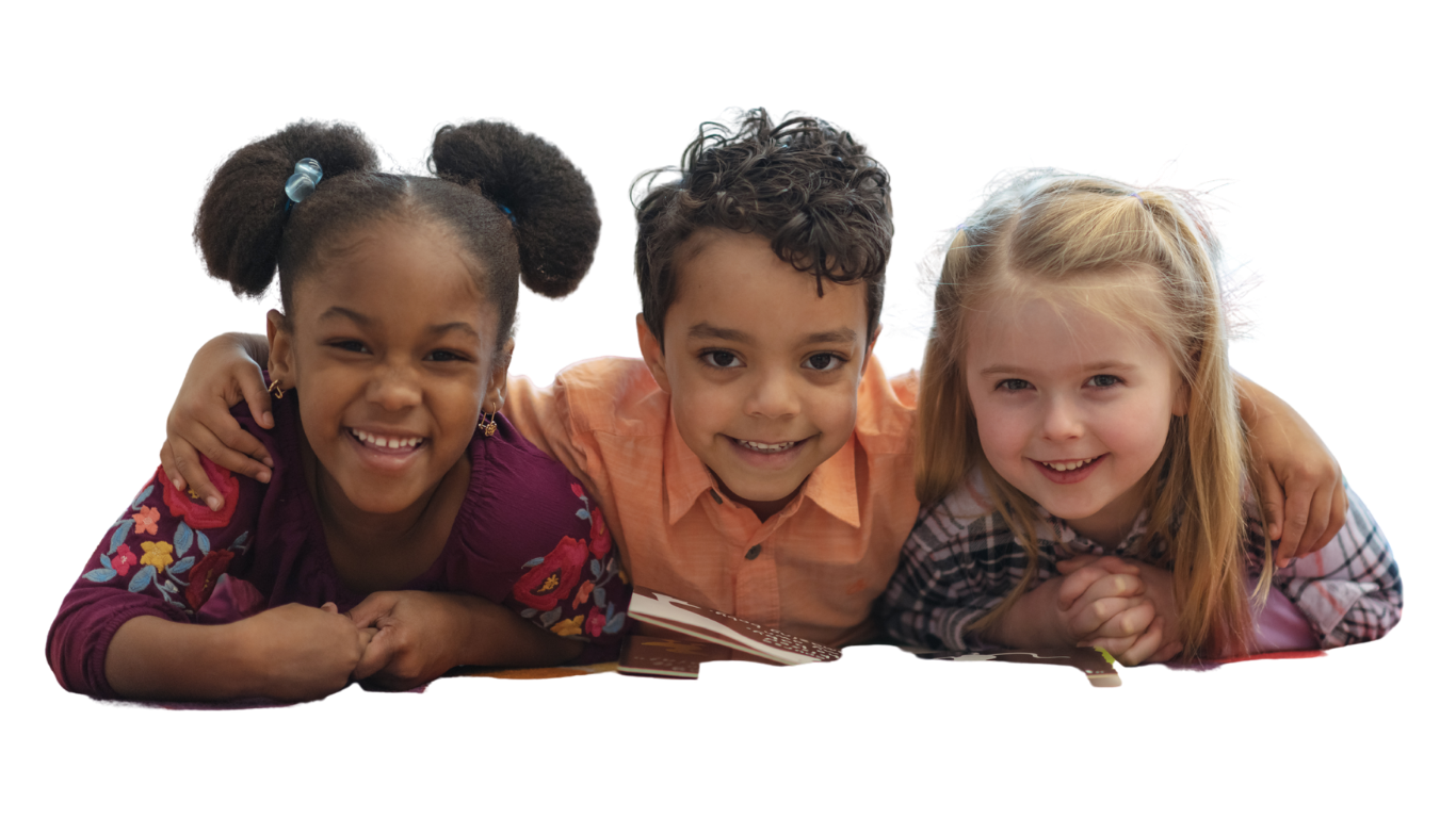 Three children lying on the floor with their arms around each other, smiling at the camera.