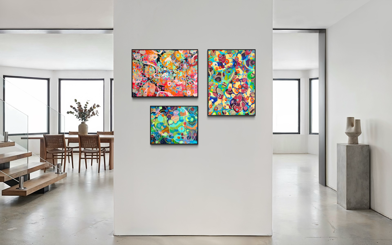 Tre quadri astratti con colori vivaci appesi su una parete bianca all'interno di un ambiente moderno