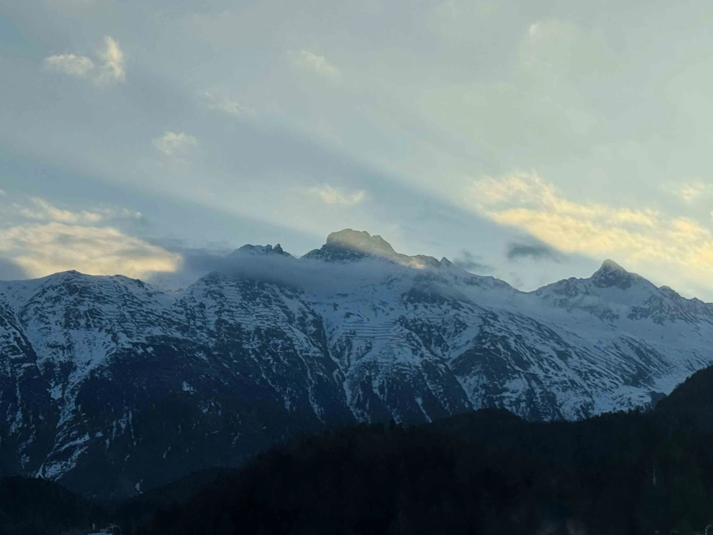 Montagne innevate con cielo nuvoloso e alcune nuvole leggere