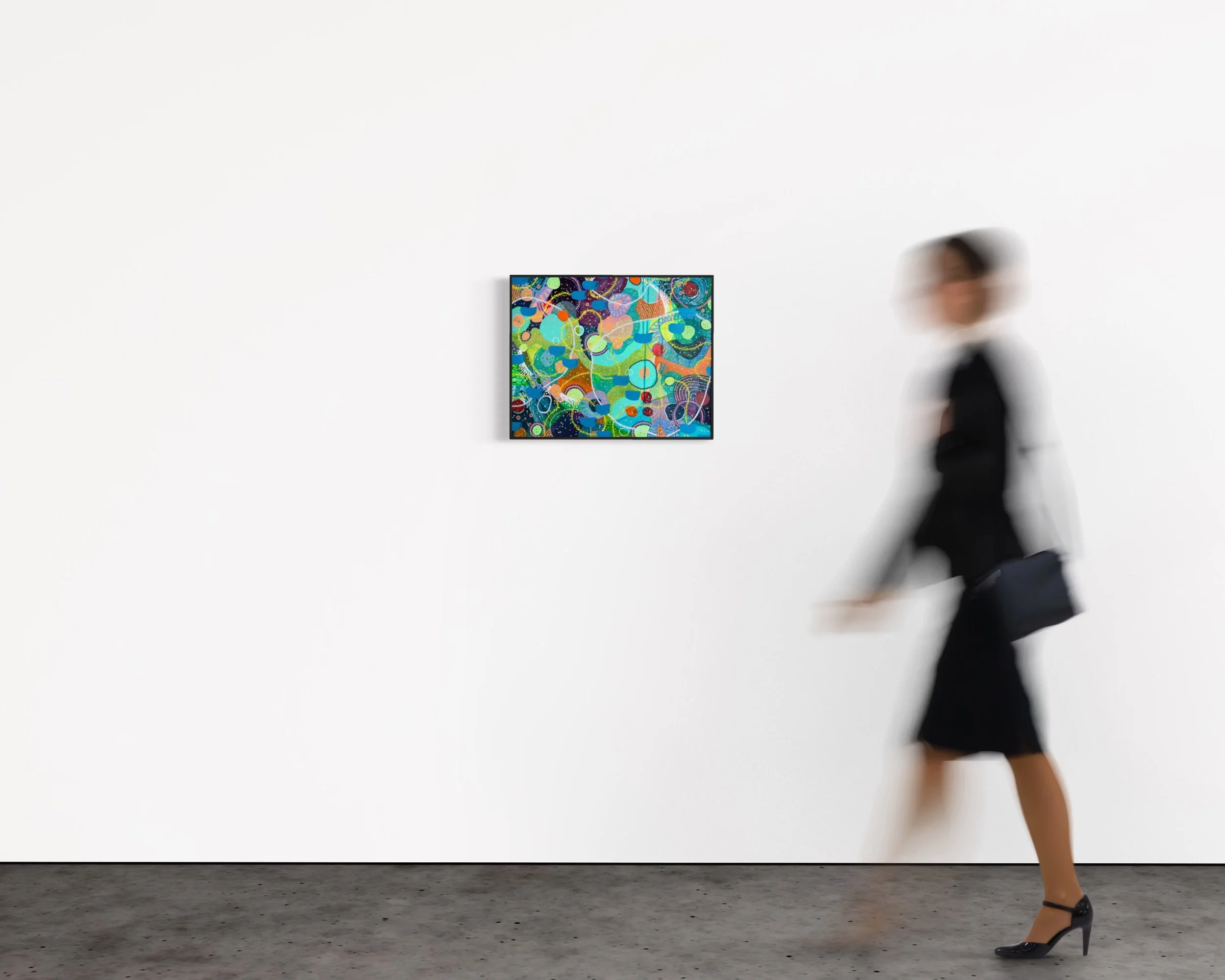 Persone che camminano in un museo con pareti bianche e un dipinto colorato.