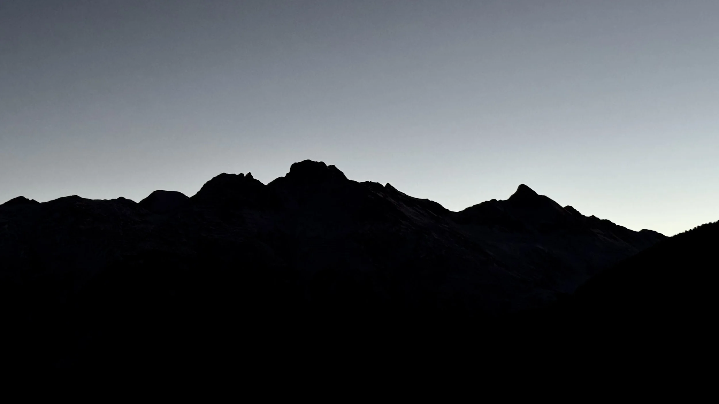 Silhouette di montagne contro un cielo chiaro al tramonto o all'alba.