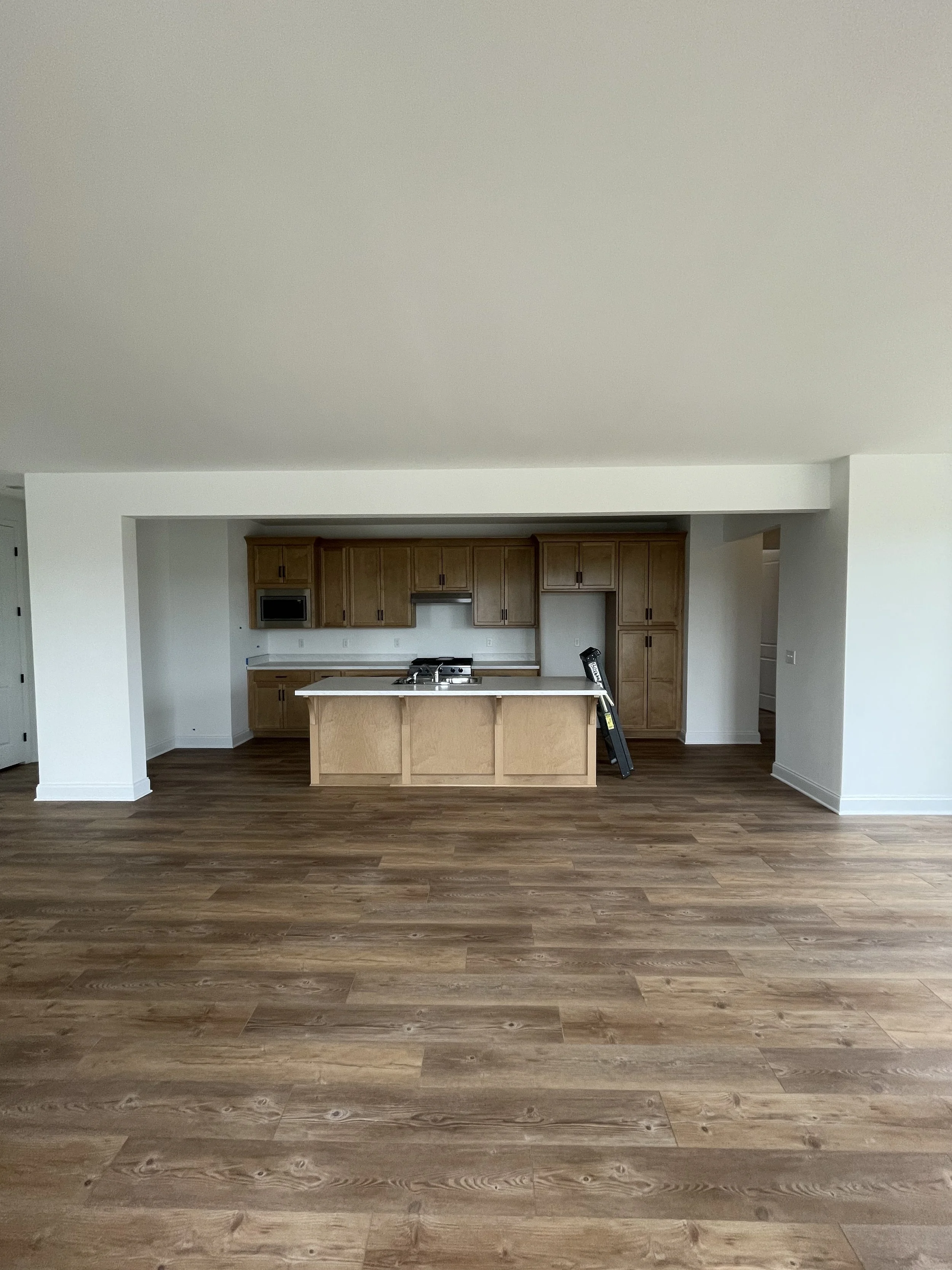 Empty kitchen with wooden cabinets, a kitchen island, and wood flooring.