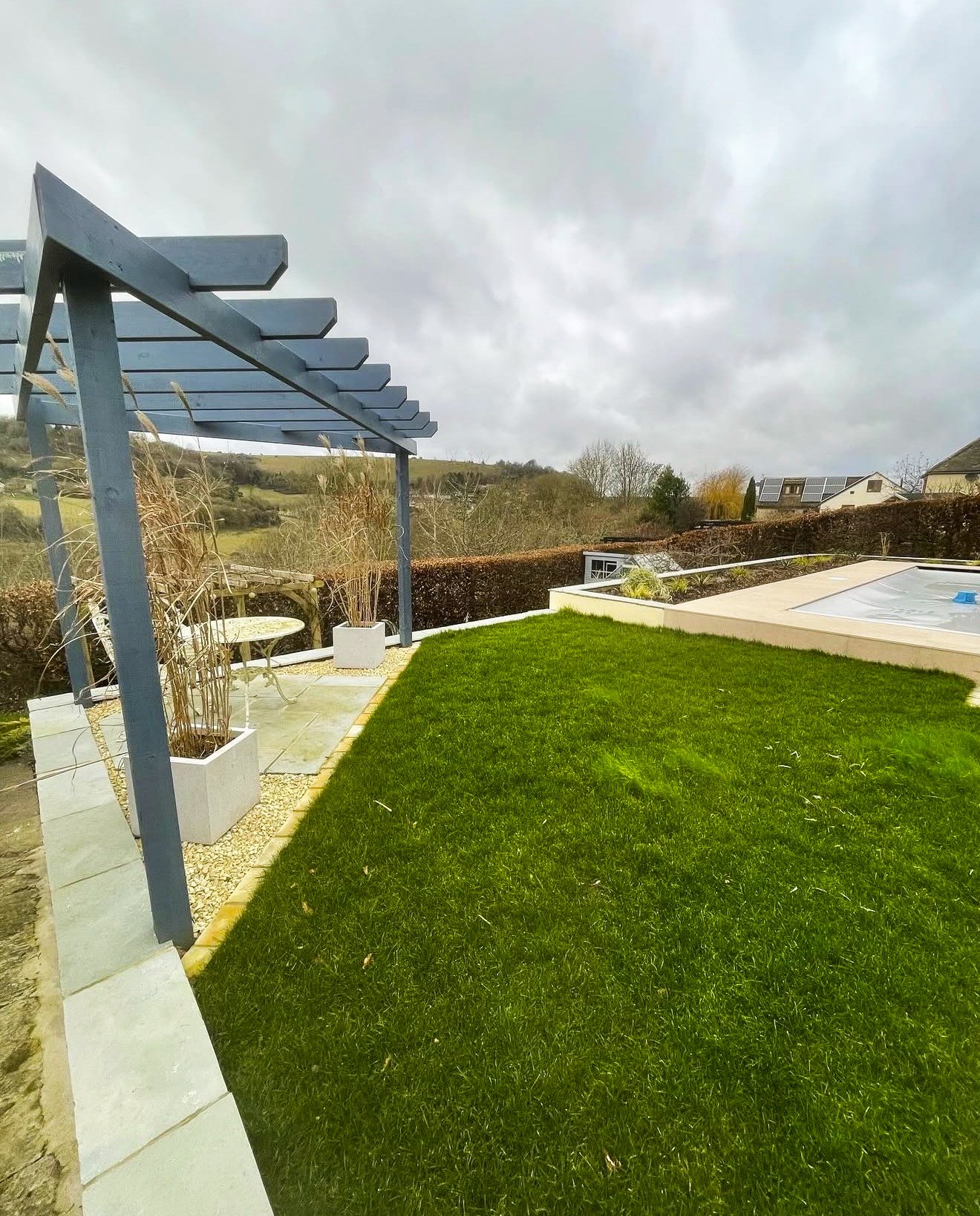 A complete redesign with - stone slabs finishing off round the pool, new turf, edging and a pergola.