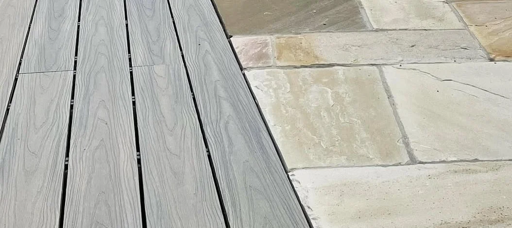 Close-up of a section of grey composite wooden decking and patio slabs