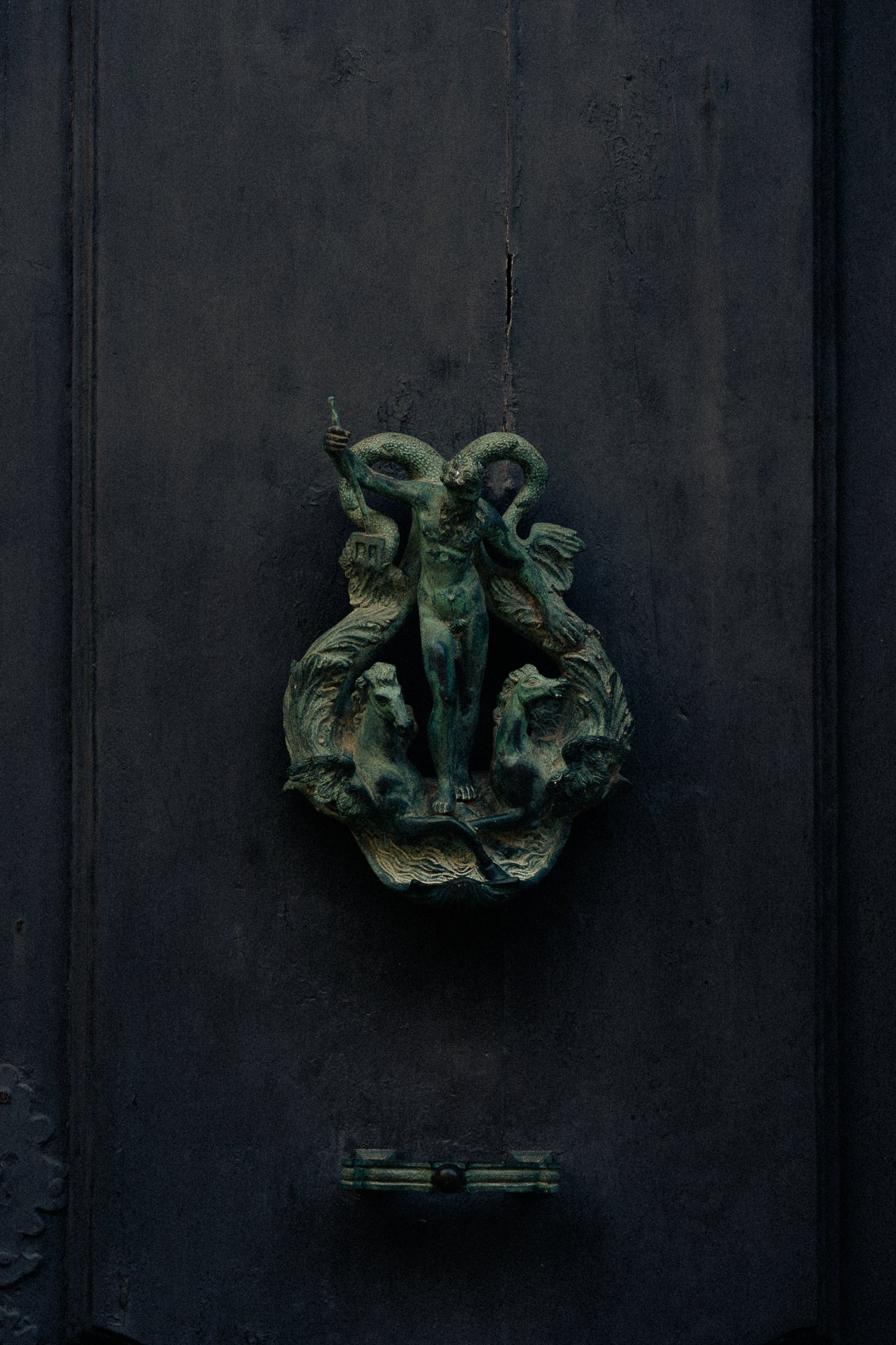 Green sculptural door knocker on a dark door, artisanal detail for boutique hotel and heritage design aesthetics