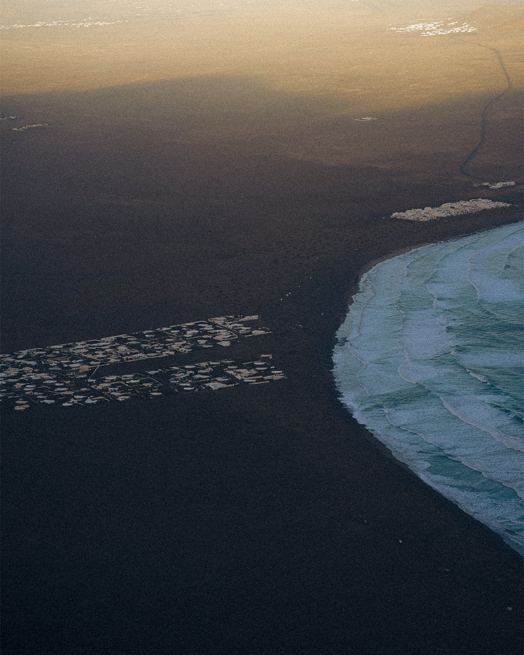 Aerial coastline view at dusk with ocean curve, serene “quiet stay” mood for boutique hotel marketing in Lanzarote
