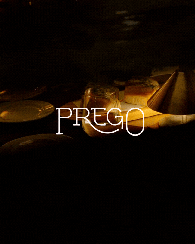 Mesa con pan, vino, platos y lámpara en un ambiente oscuro y acogedor.