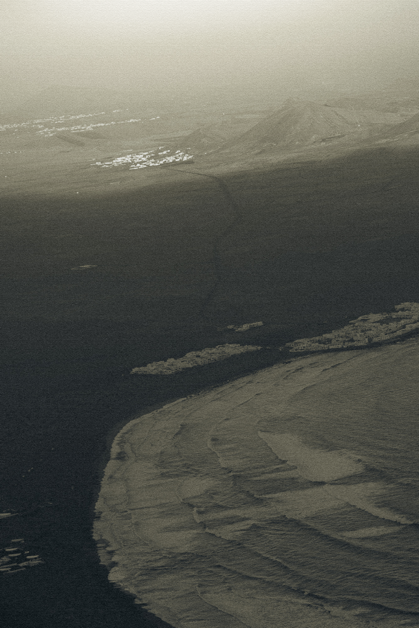 Moody aerial shoreline detail in monochrome tones, calm coastal texture for quiet luxury travel branding in Lanzarote Spain