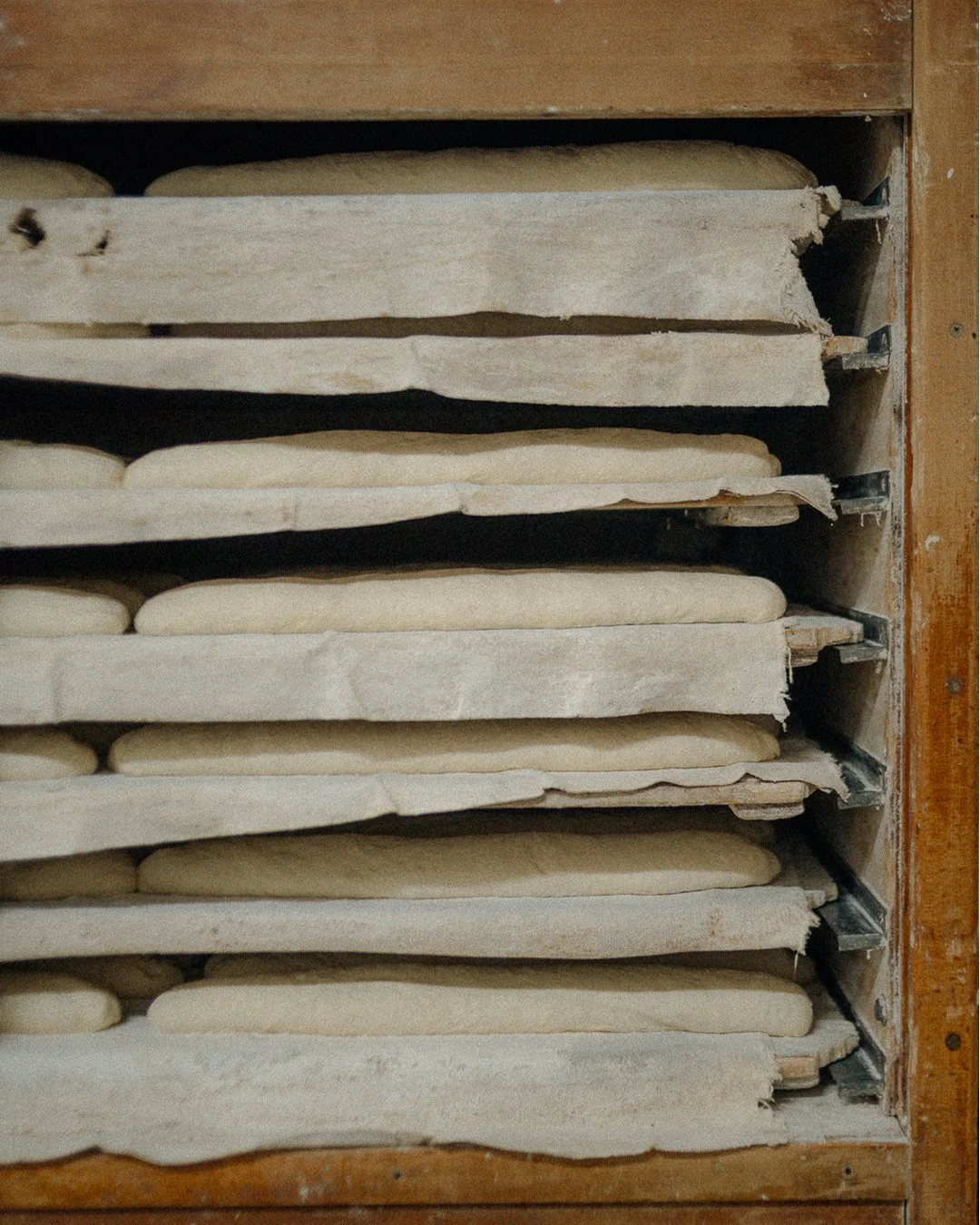 Raw bread loaves resting on linen-lined wooden proofing racks at Horno El Reloj traditional bakery, El Cabanyal, Valencia