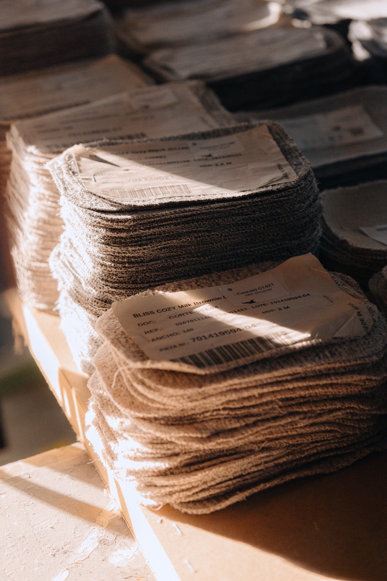 Stack of textured papers in warm light, tactile material detail for design-led hospitality and editorial content
