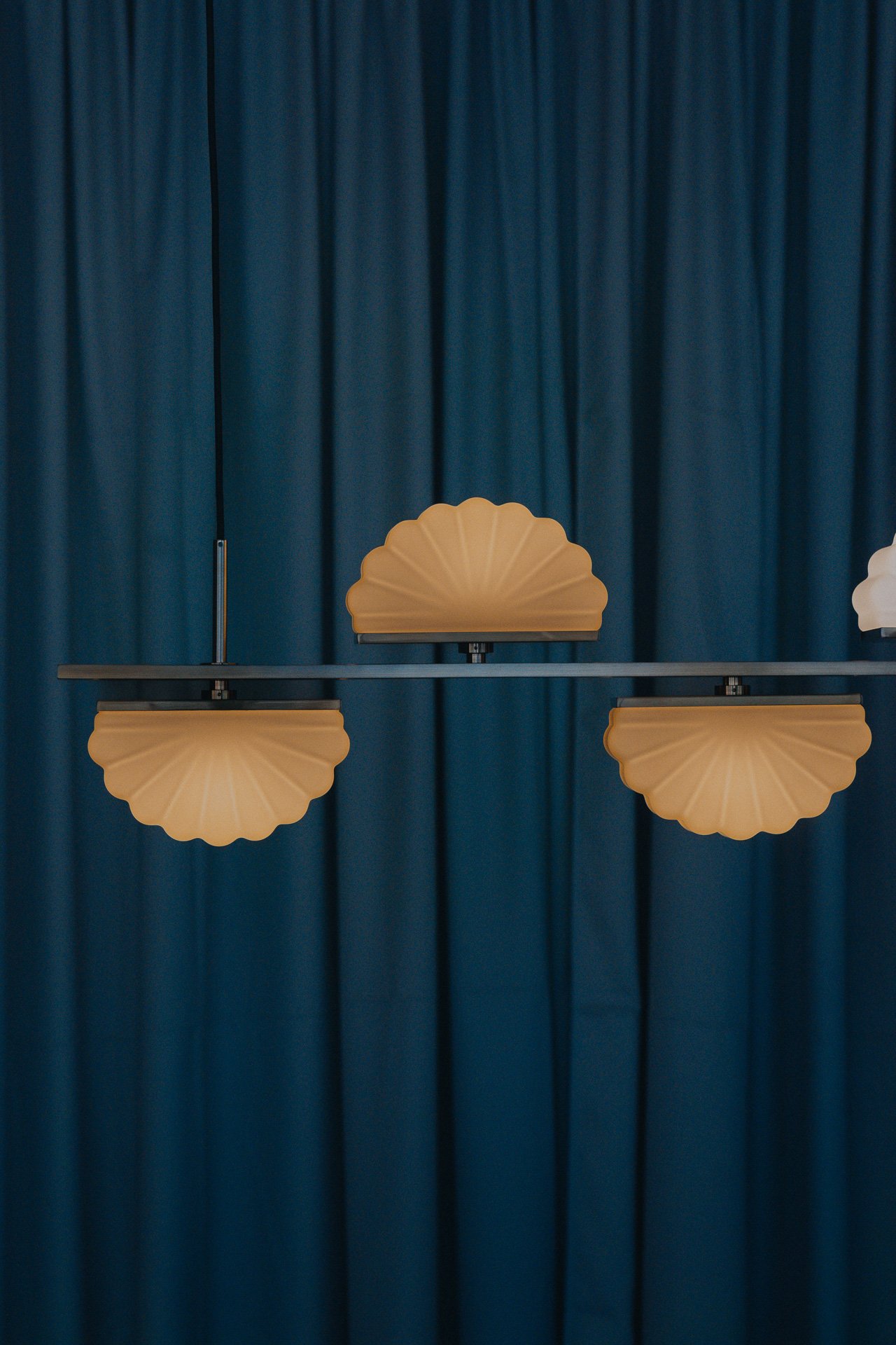 Symmetrical pendant lights against deep blue curtains, design-forward interior detail for boutique hotel branding