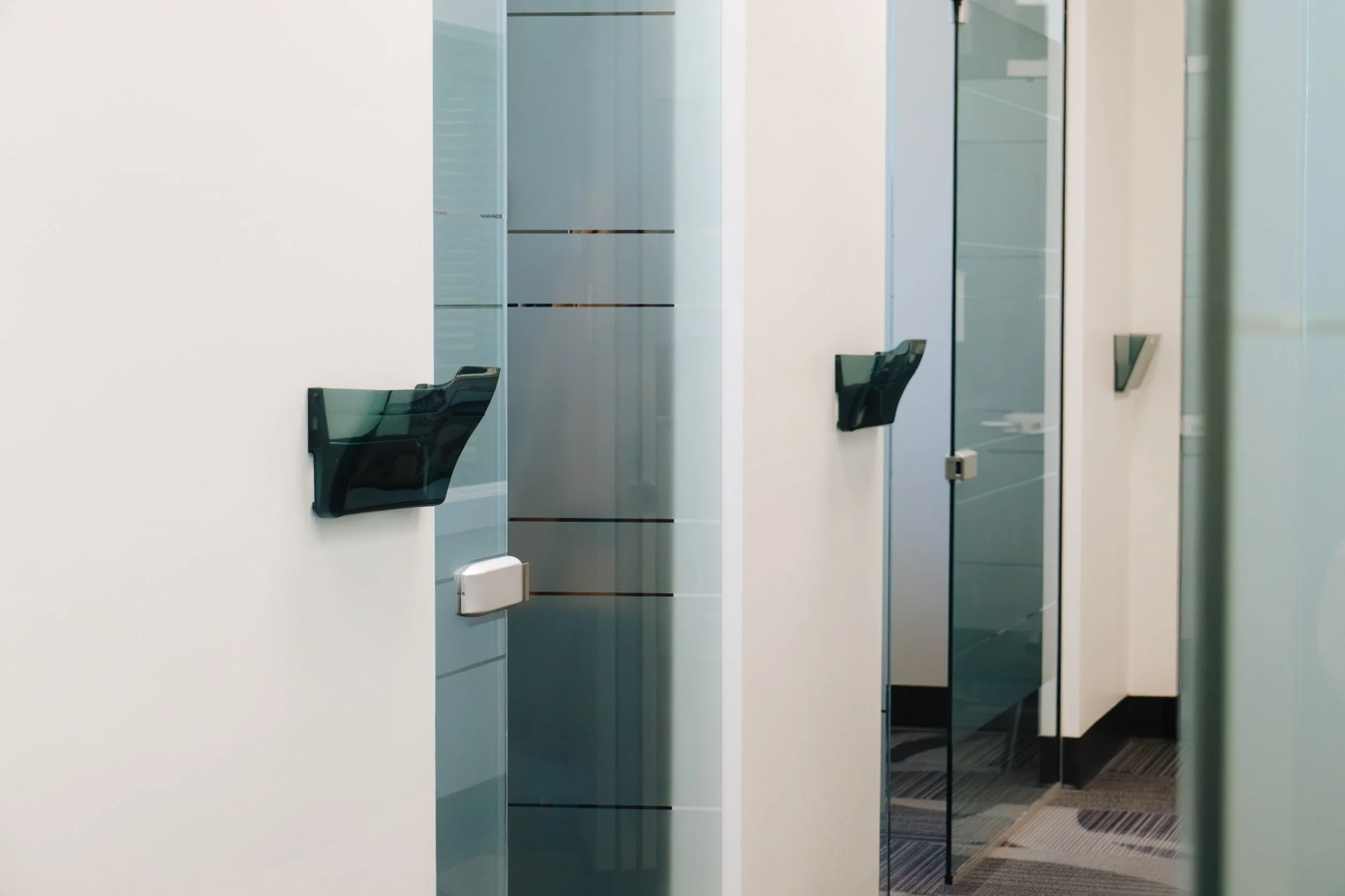 Office hallway with frosted glass doors and black wall-mounted holders.