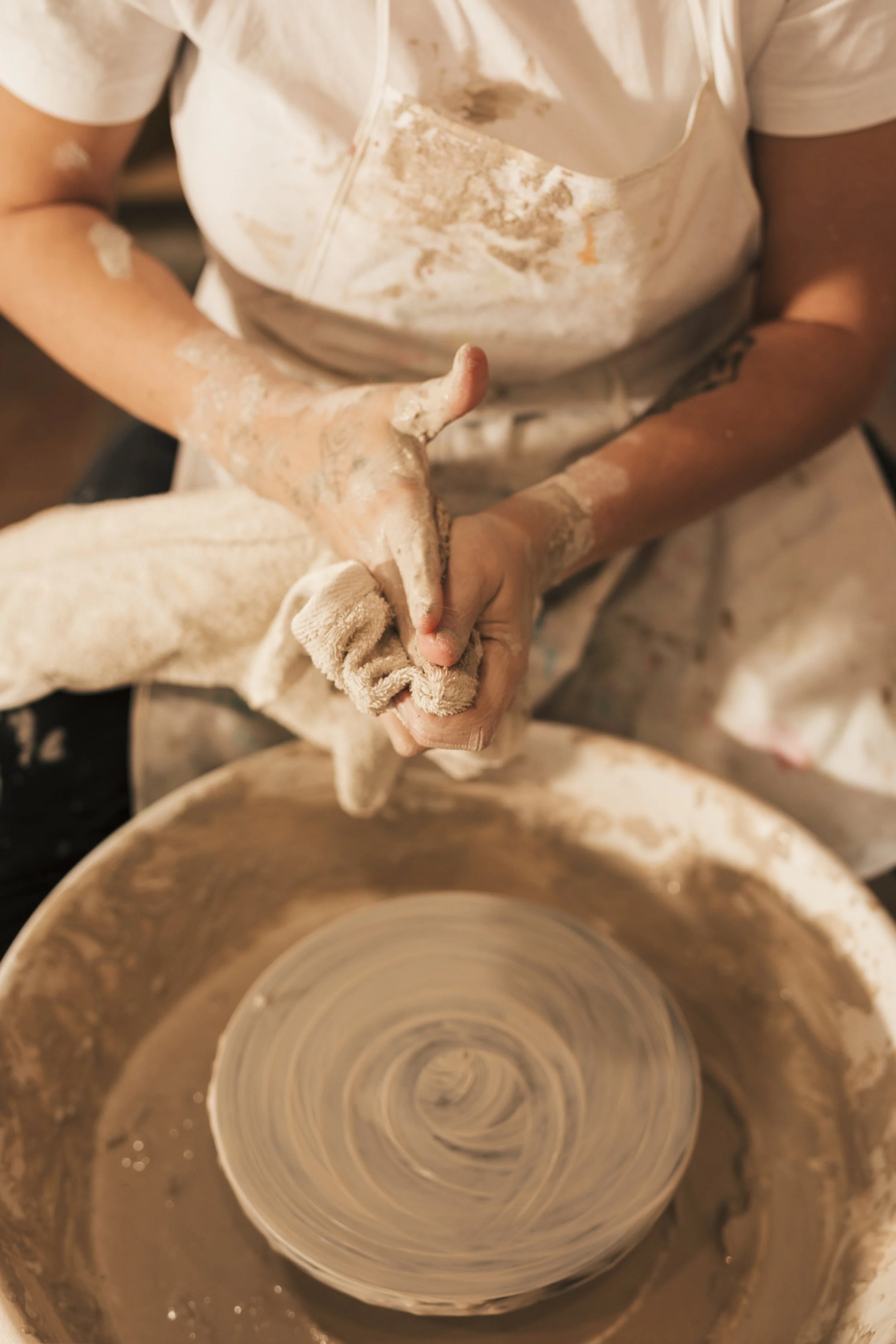 female-s-potter-sitting-near-pottery-wheel-cleaning-her-hands-with-napkin.jpg