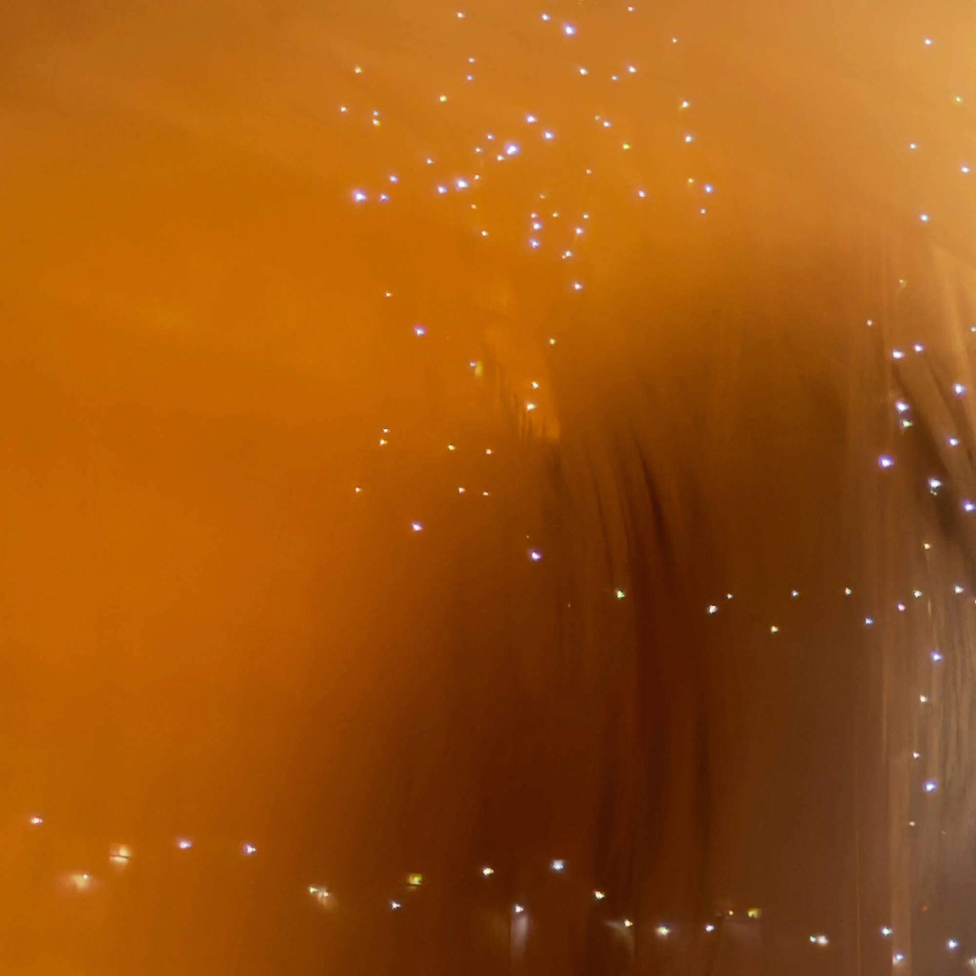 Close-up of a wooden surface with small glowing fairy lights scattered across it.