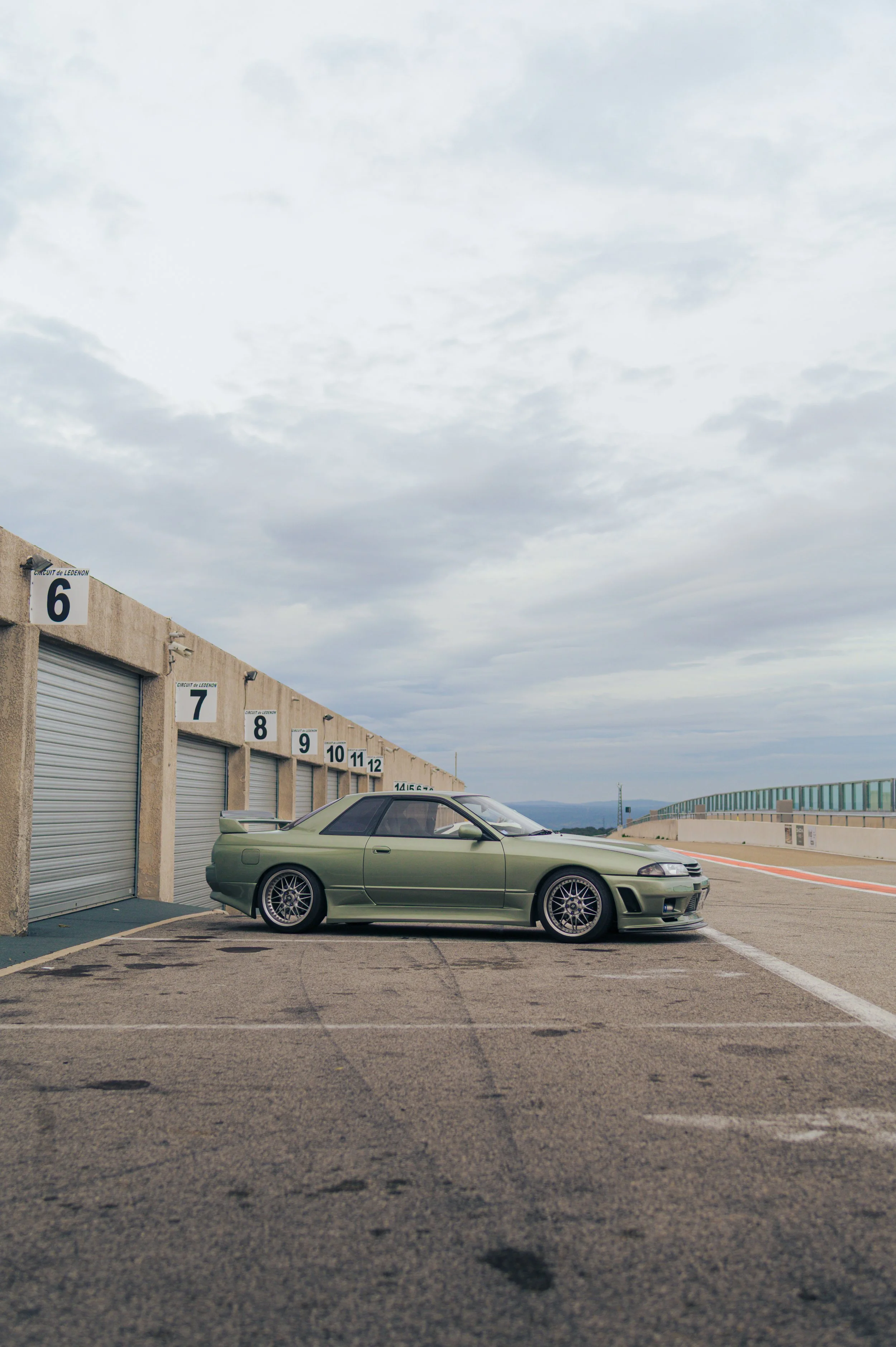 Nissan Skyline R32 in Millenium Jade parked in the pit lane at a track day on the Ledenon racetrack.