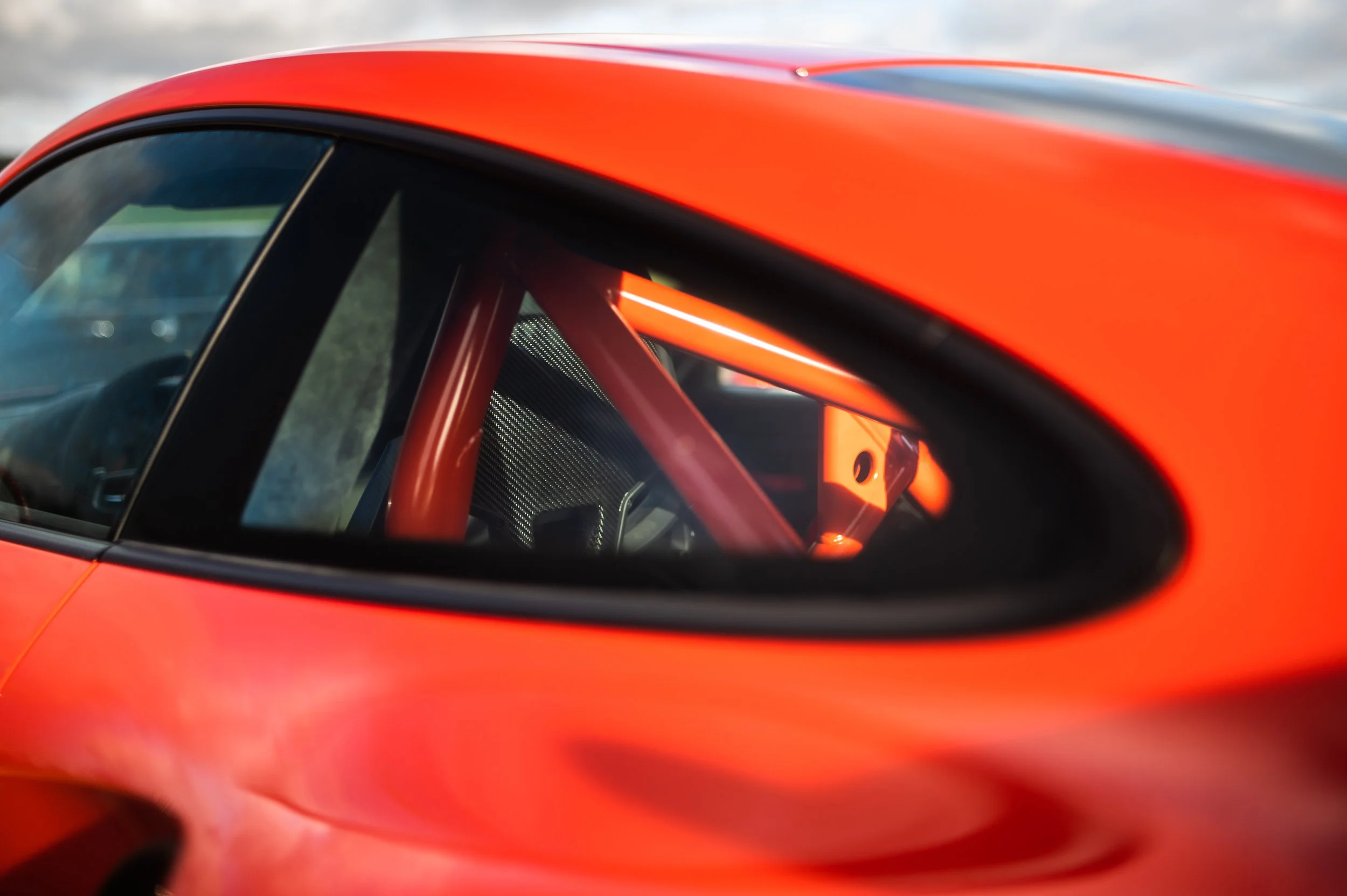 Close-up of a Porsche 911 (991.1) GT3RS showing a portion of the window, interior roll cage, and seat.