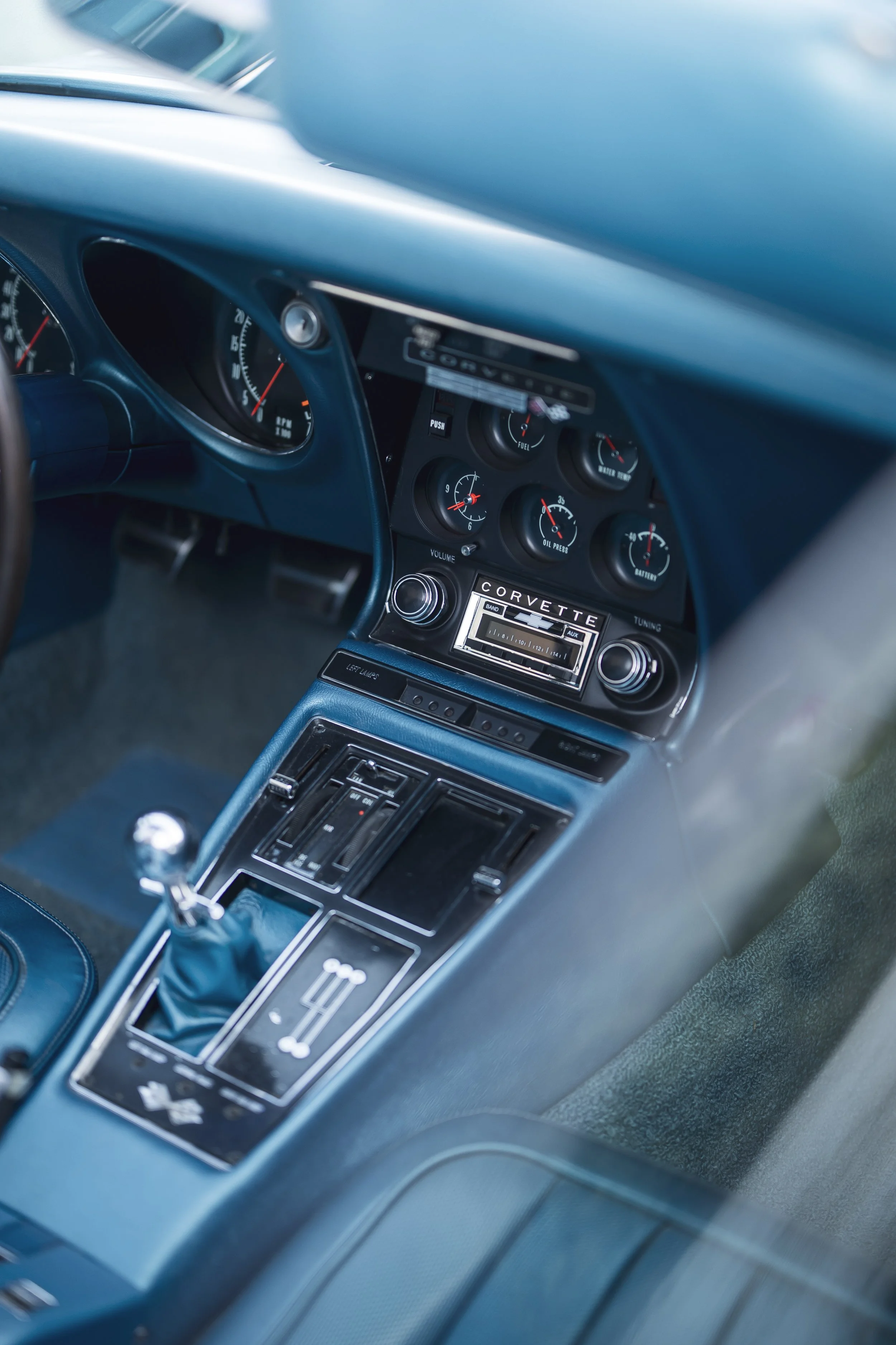 Interior of a vintage sports car, focusing on the dashboard and center console, including gauges, radio, and gear shift.