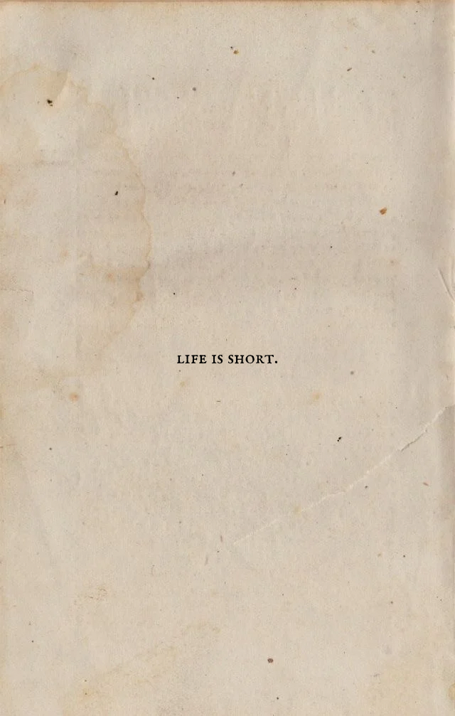 A piece of aged paper with the words "LIFE IS SHORT." printed in the center.