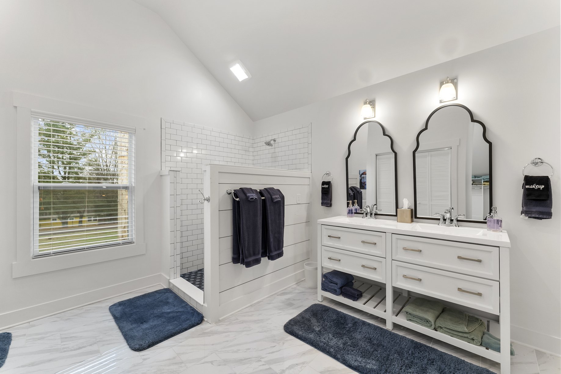 Bright bathroom with a double-sink vanity, arched mirrors, fresh linens, and natural light in a Ball Ground, Georgia vacation rental.