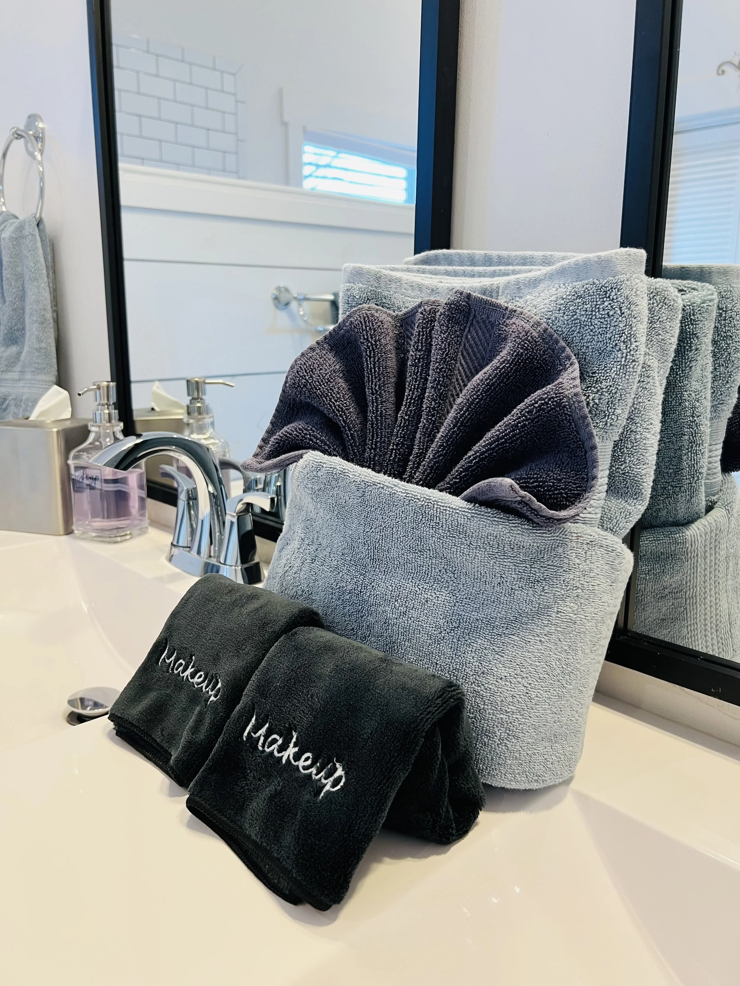 Elegantly folded blue and black towels on bathroom sink with at Ball Ground Vacation Rental