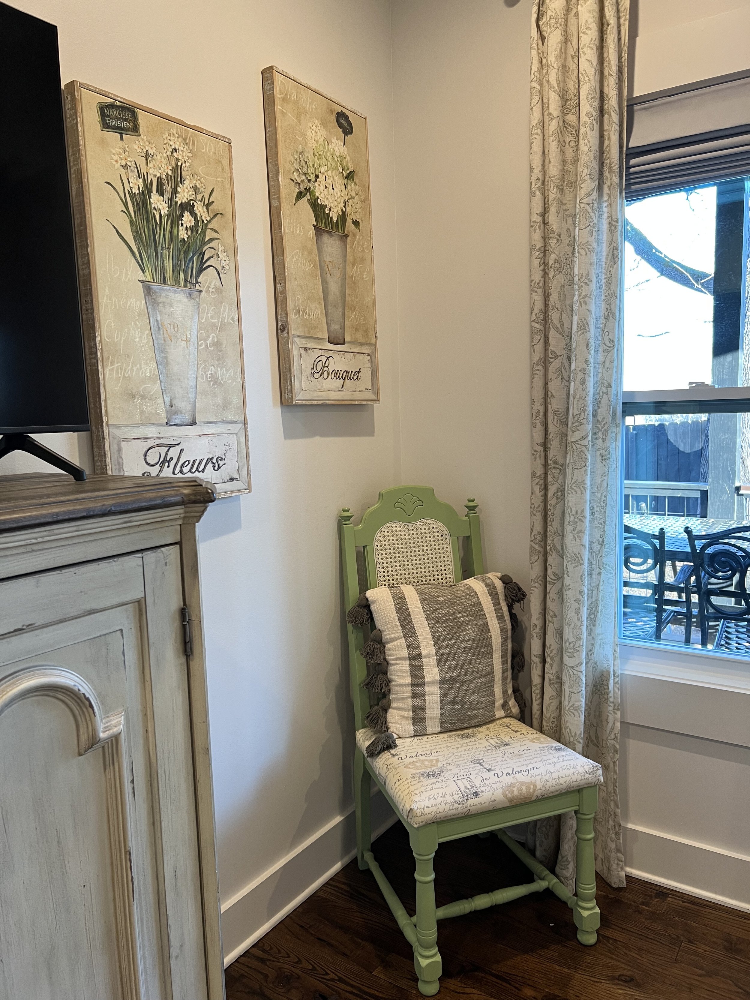 Charming bedroom seating area with a vintage chair, decorative accents, and window views in a peaceful Ball Ground, GA short-term rental.