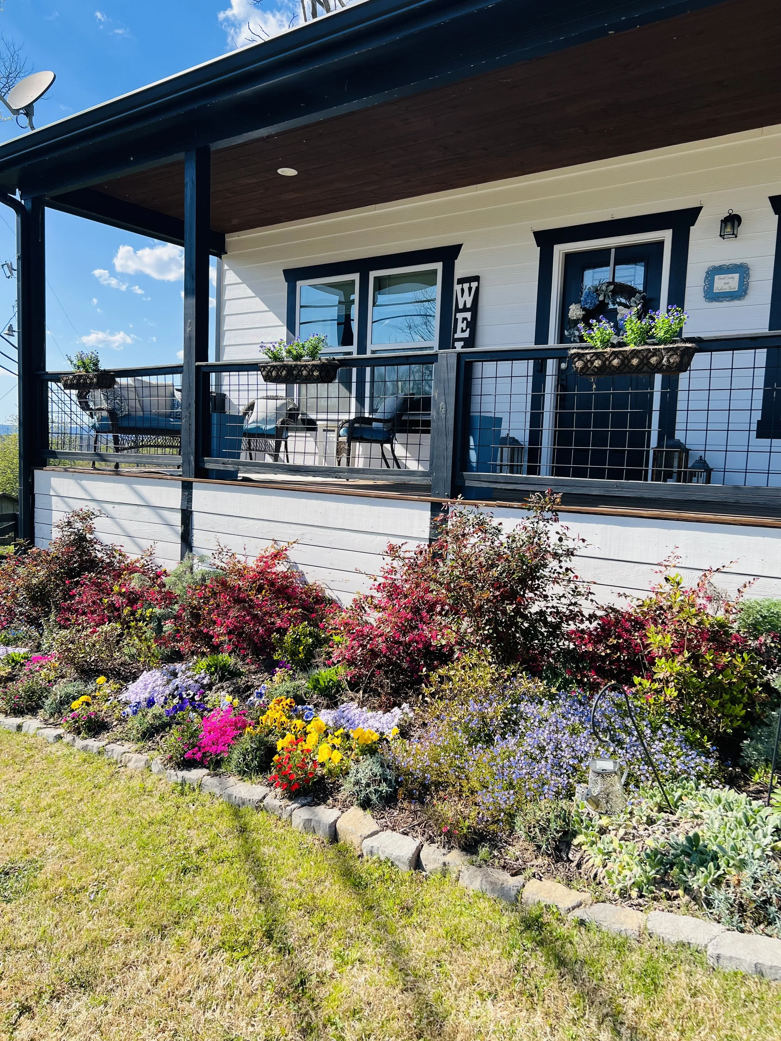 Charming front porch with outdoor seating, flower planters, and manicured landscaping at a French country–inspired Ball Ground, GA short-term rental.