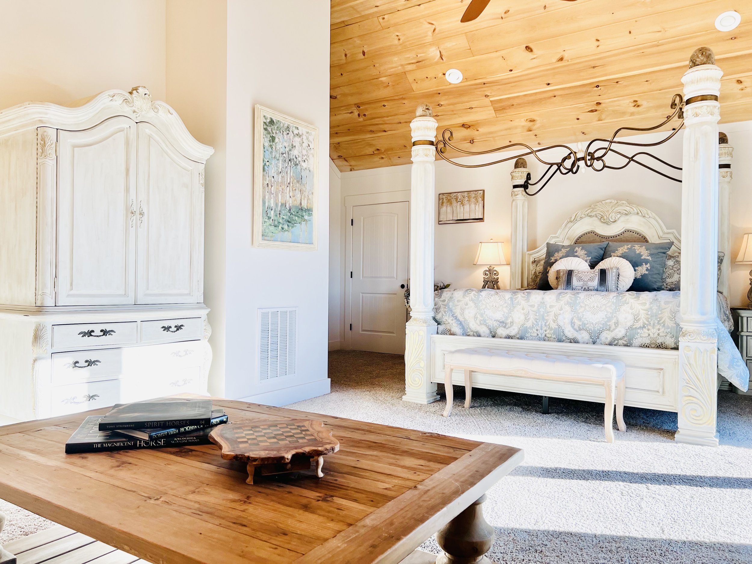 Bright and airy four-poster guest bedroom with classic furnishings, cozy lighting, and French country charm at a peaceful Ball Ground, GA short-term rental.