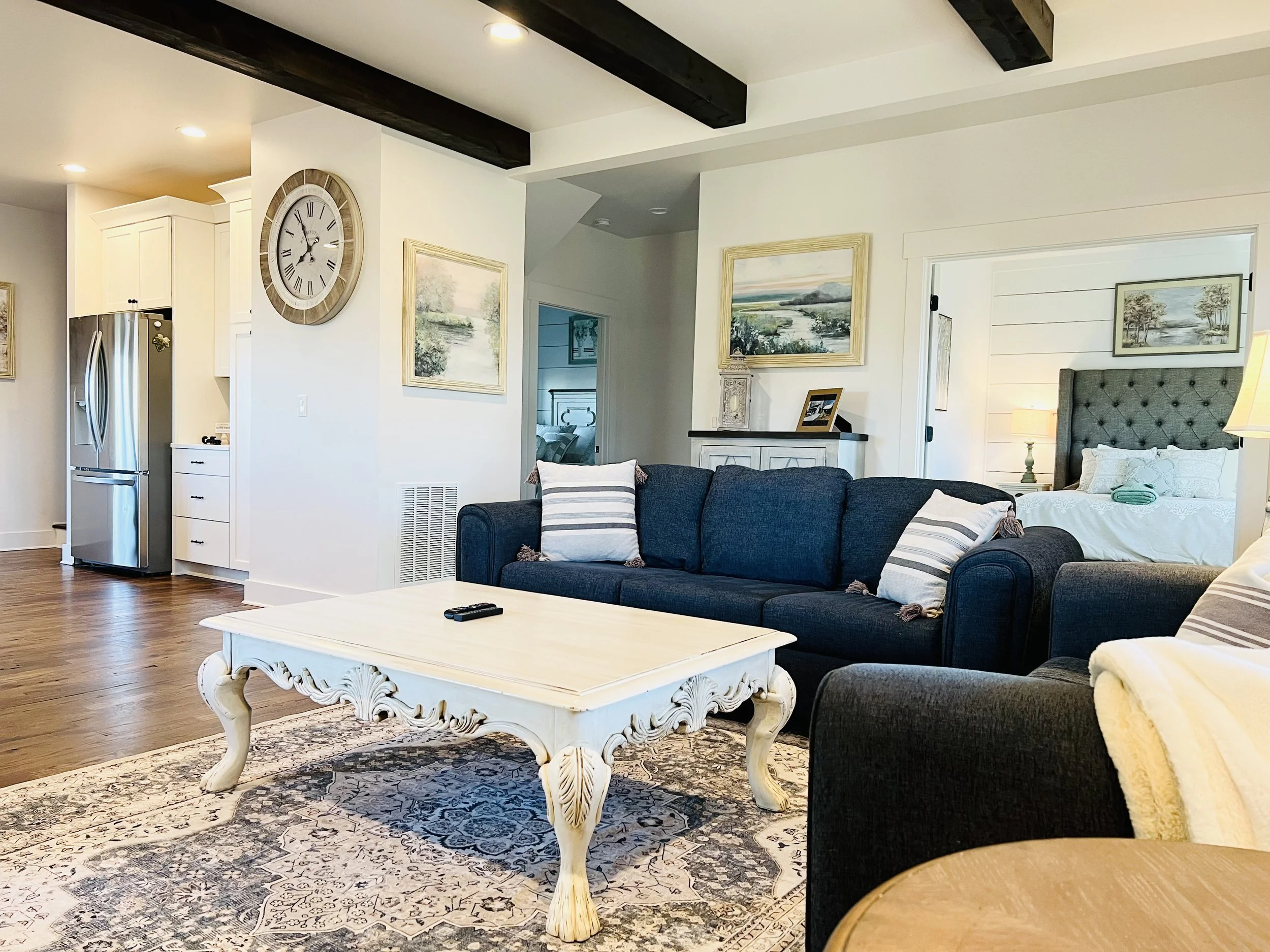 Open-concept living room with French country decor, navy and white seating, elegant sideboard, and large windows, connecting to the kitchen at a Ball Ground, Georgia vacation rental