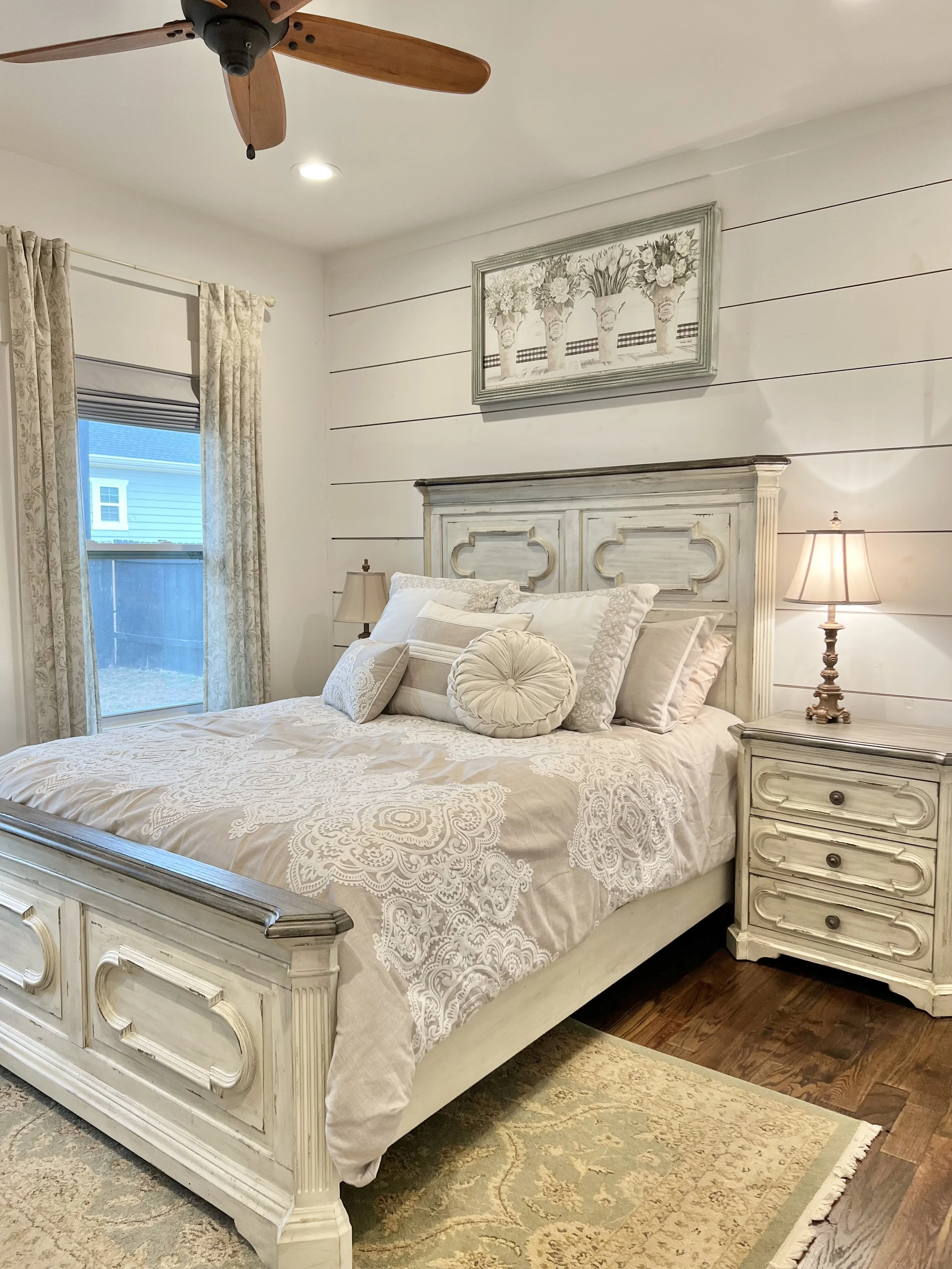 Serene guest bedroom with white nightstands, soft lighting, floral accents, and hardwood floors in a French country–style Ball Ground, Georgia vacation rental.