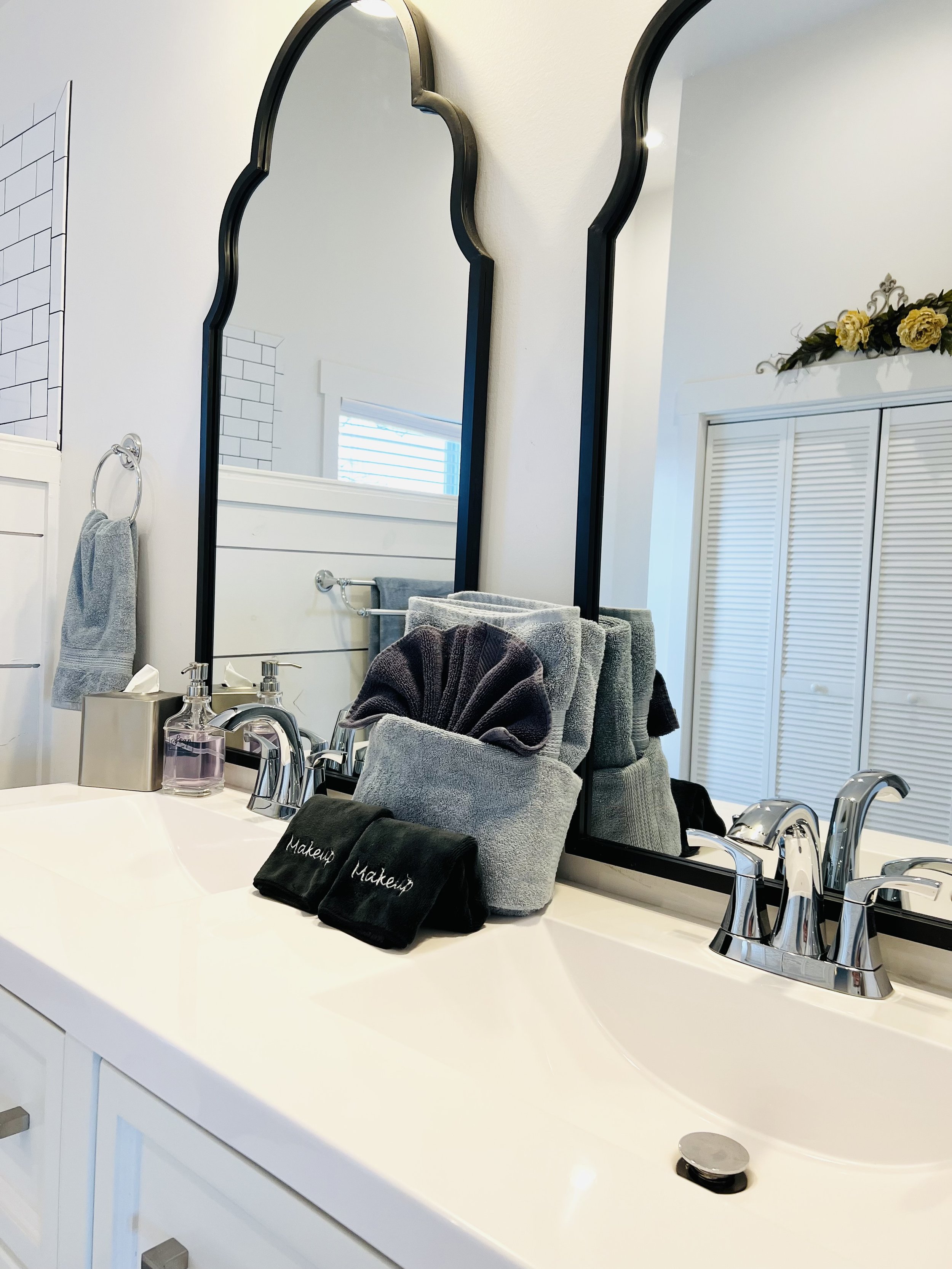 Bright bathroom with a double-sink vanity, arched mirrors, fresh linens, and natural light in a Ball Ground, Georgia vacation rental.