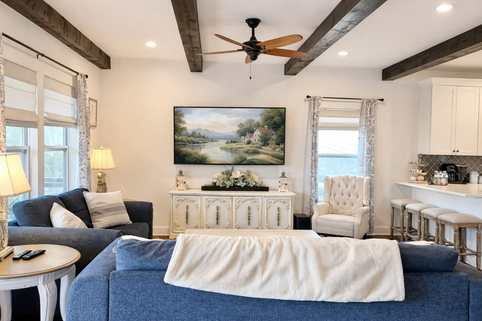 Open-concept living room with French country decor, navy and white seating, elegant sideboard, and large windows, connecting to the kitchen at a Ball Ground, Georgia vacation rental